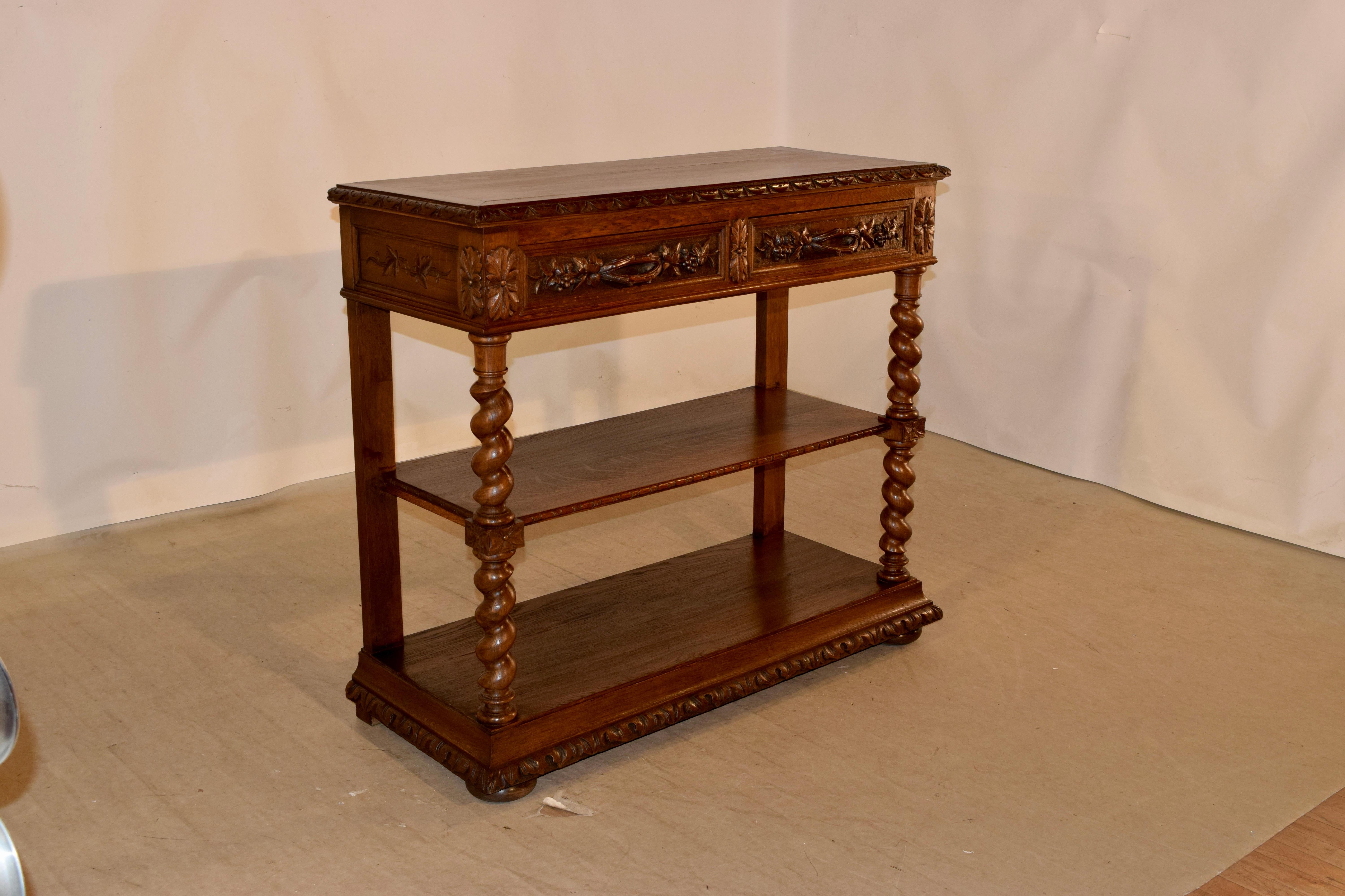 19th century oak dessert buffet from France with a banded top and a beveled and carved decorated edge, over two drawers with hand carved decorated drawer fronts along with hand carved pulls and paneled and carved sides. The legs are hand turned