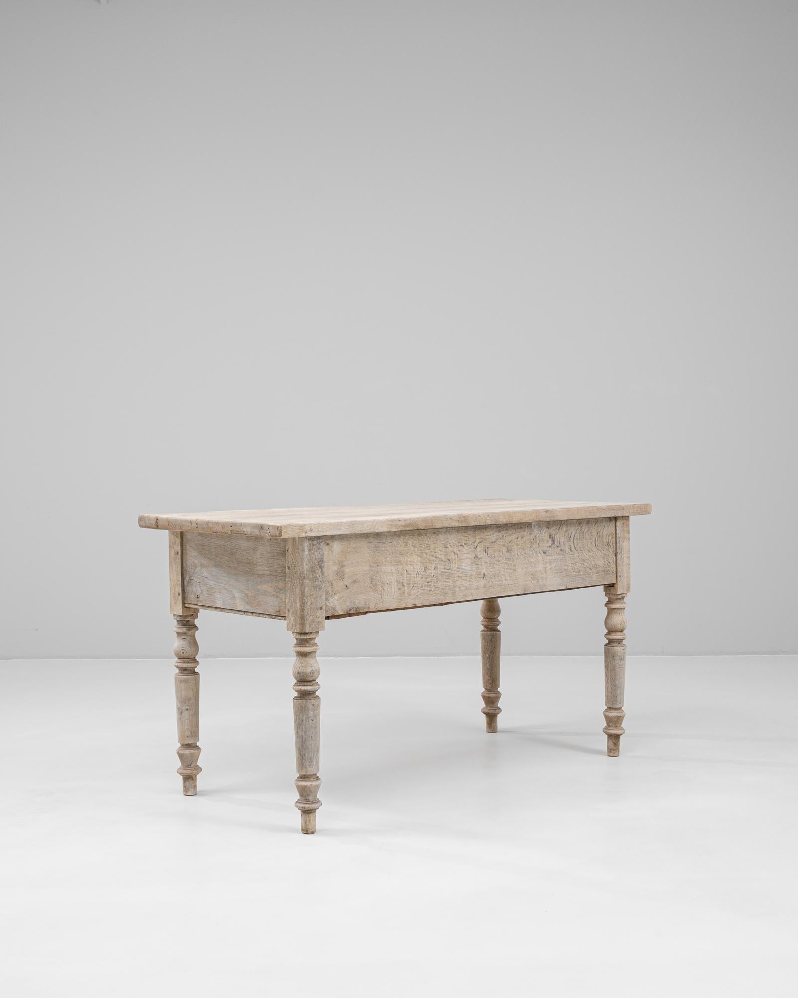 This 19th Century French oak dining table captures the charm and solidity of classic farmhouse design. Crafted from thick oak planks, the table boasts a beautifully aged, pale patina that highlights the natural grain and wear of the wood. Its