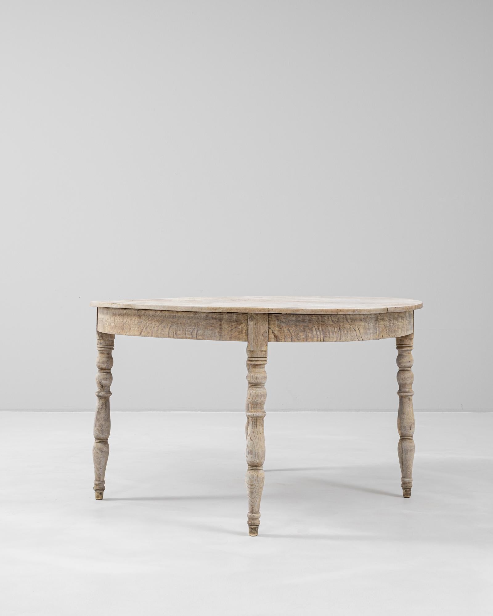 Questo tavolo da pranzo in rovere francese del XIX secolo cattura l'eleganza e l'utilità dell'artigianato di provincia. Caratterizzato da una silhouette demi-lune con una sottile spaccatura al centro - che suggerisce che in origine poteva ospitare