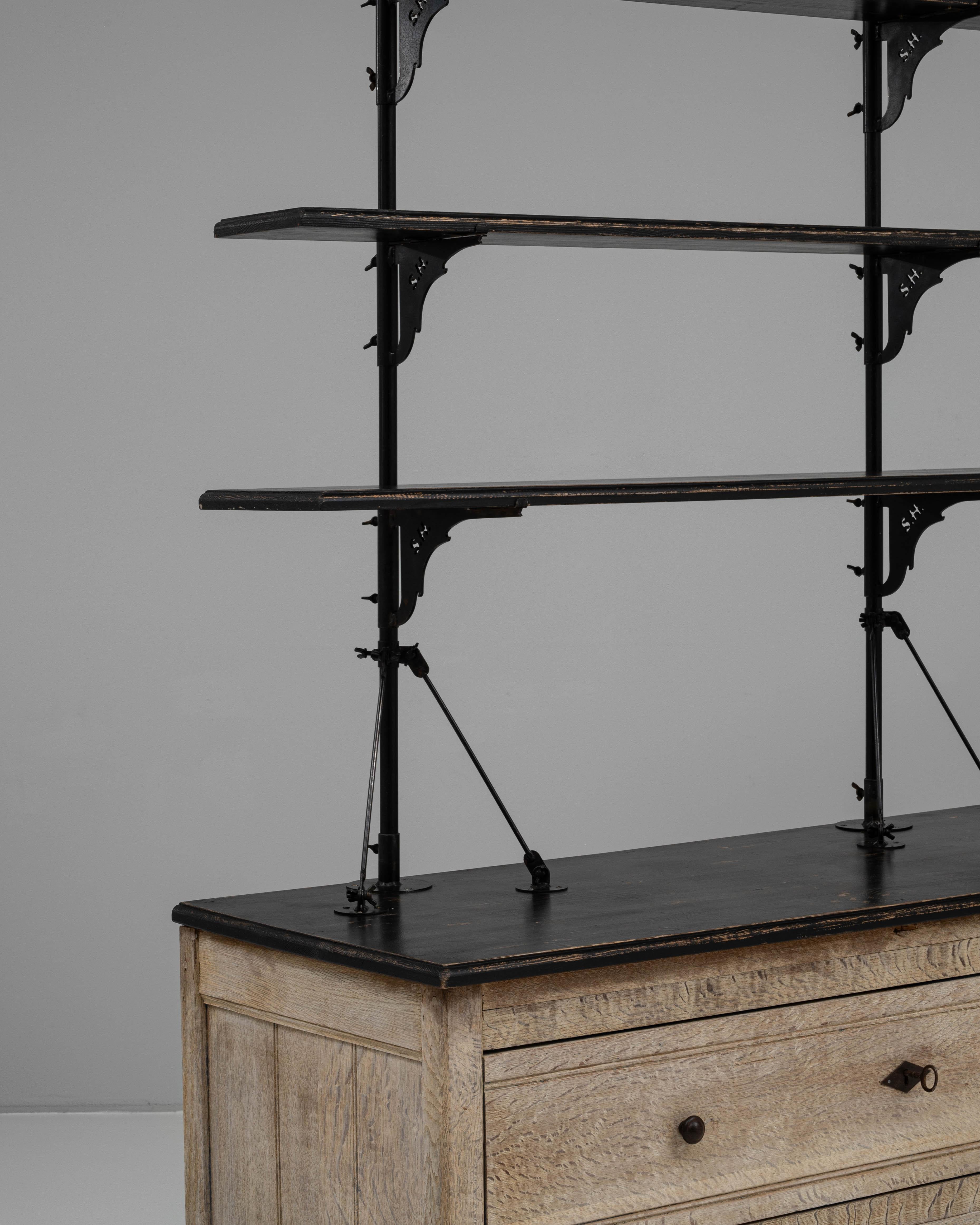 This 19th Century French oak display cabinet is a distinctive blend of utility and architectural elegance. The base features two wide drawers with diamond-shaped escutcheons and simple wooden knobs, all framed by subtle molding and resting on