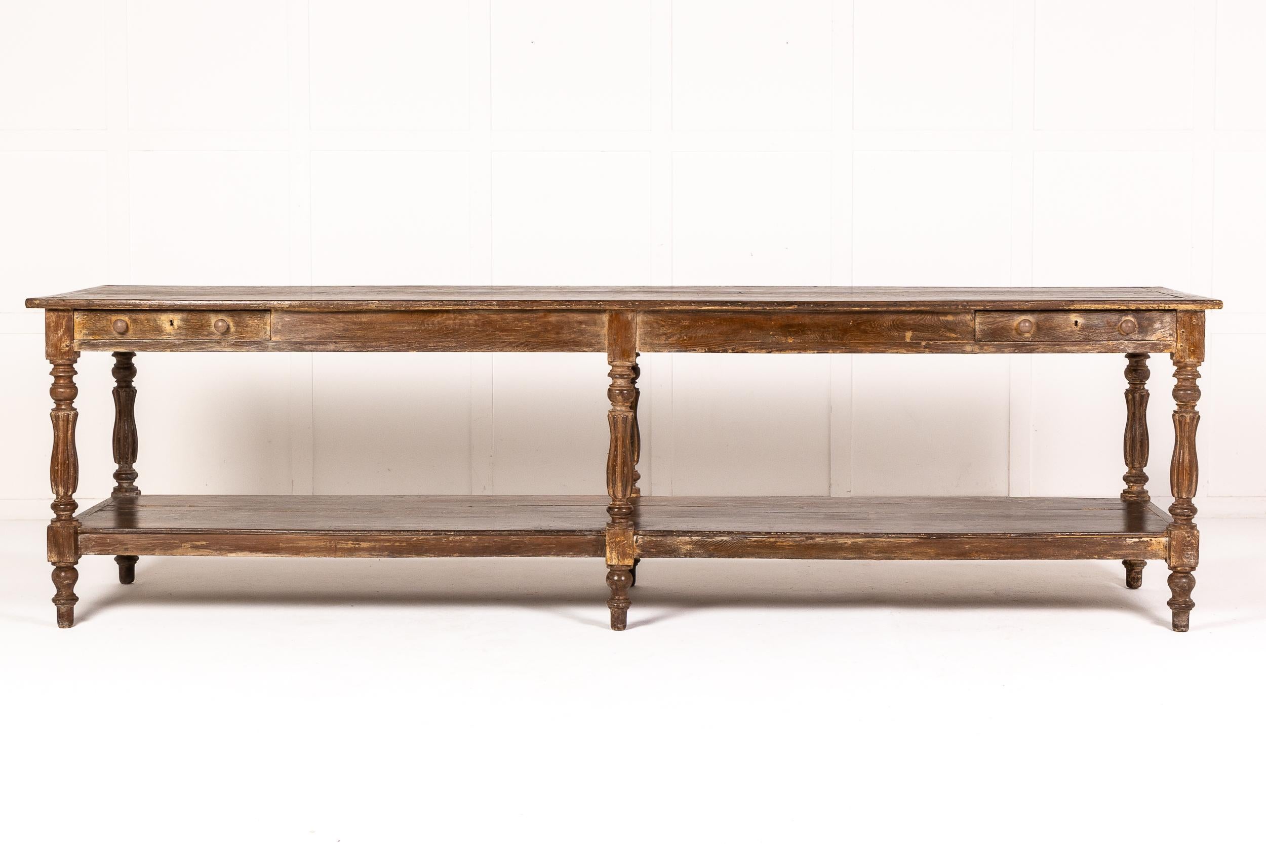 19th century French oak drapers table with very old paint finish. With an edged plank top above a narrow frieze containing two small drawers at each end. The lower shelf is joined by six well turned legs and feet.

Ideal for a serving or hall