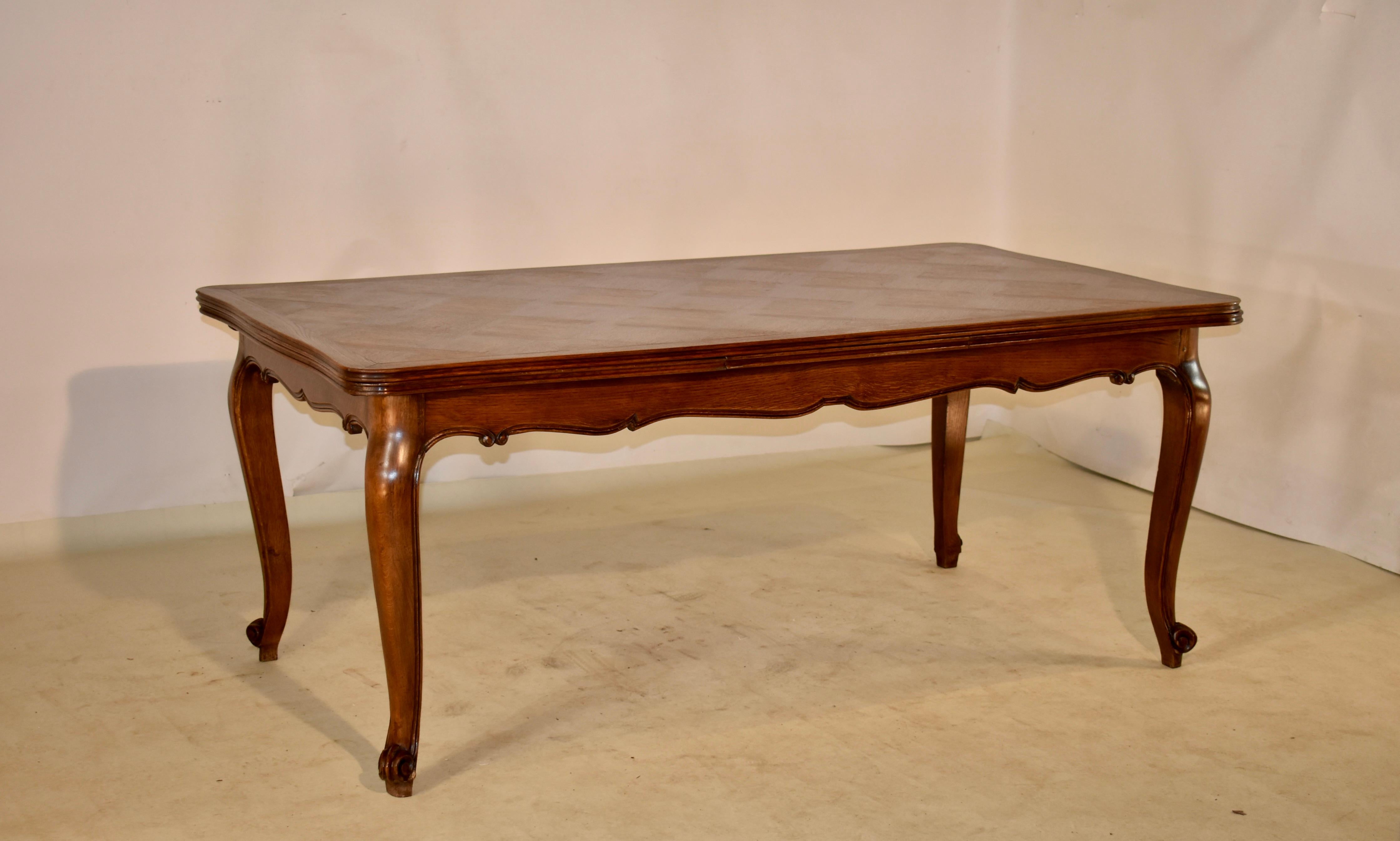 Late 19th century French draw leaf table made from oak with a banded and parqueted top and two extending leaves, following down to a hand scalloped and carved decorated apron and supported on hand carved cabriole legs with carved shell decorations
