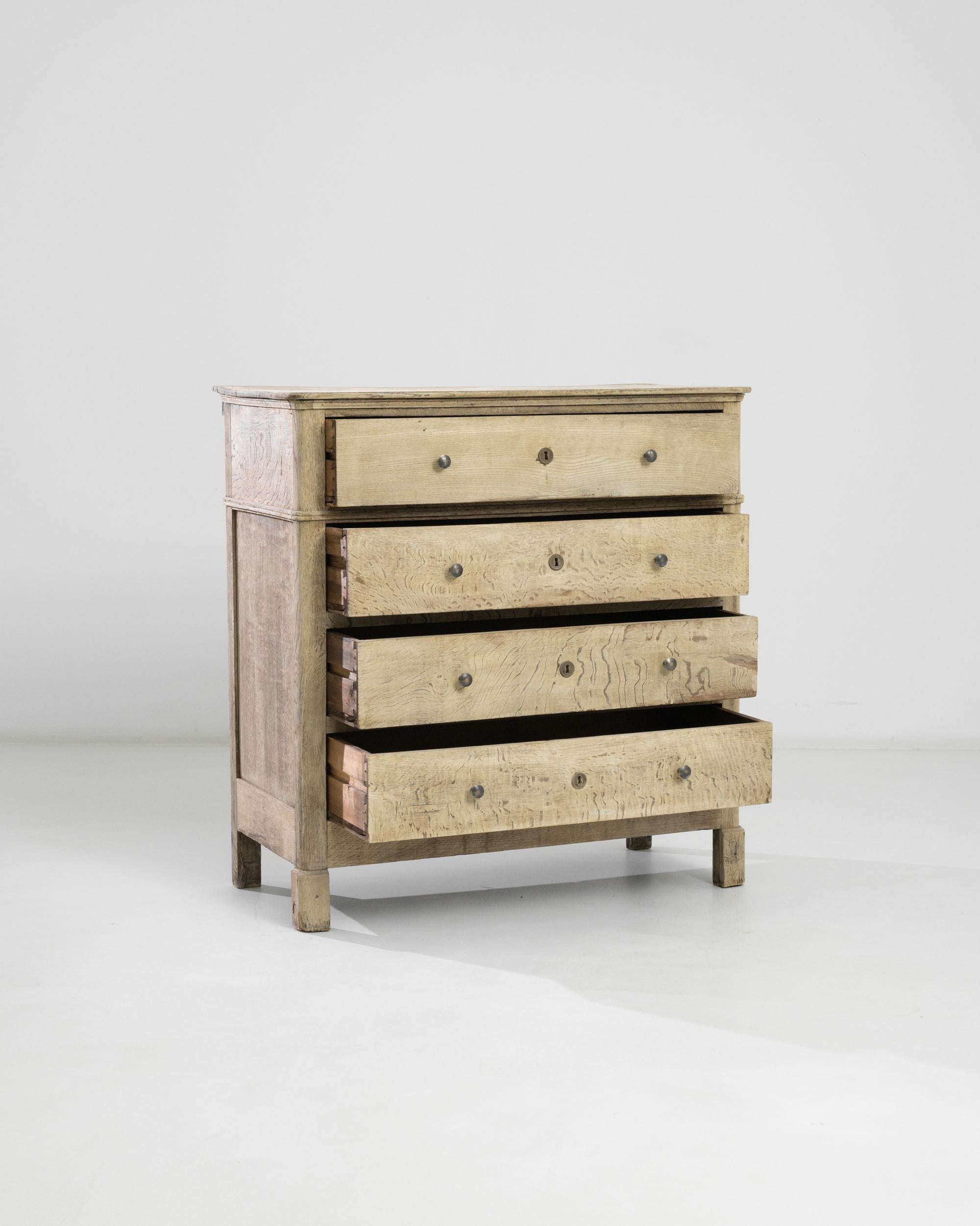Made in France circa 1880, this oak chest features four deep drawers with original pulls and locks whose roundness makes a contrast with the rectangular-shaped feet. Practical and elegant, this antique chest of drawers recollects the memories of