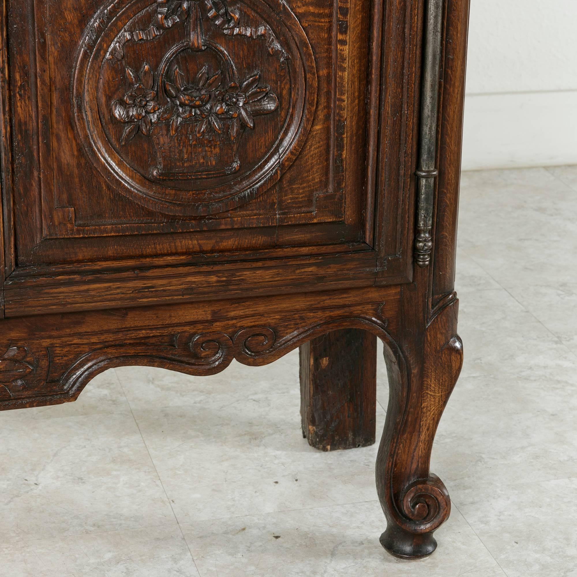 This 19th century hand carved oak Louis XV style vitrine features Classic Normandy baskets in deep relief, long fiche hinges and original glass. The French oak has aged to a beautiful deep hue, while the hand carved ornamentation is carried across