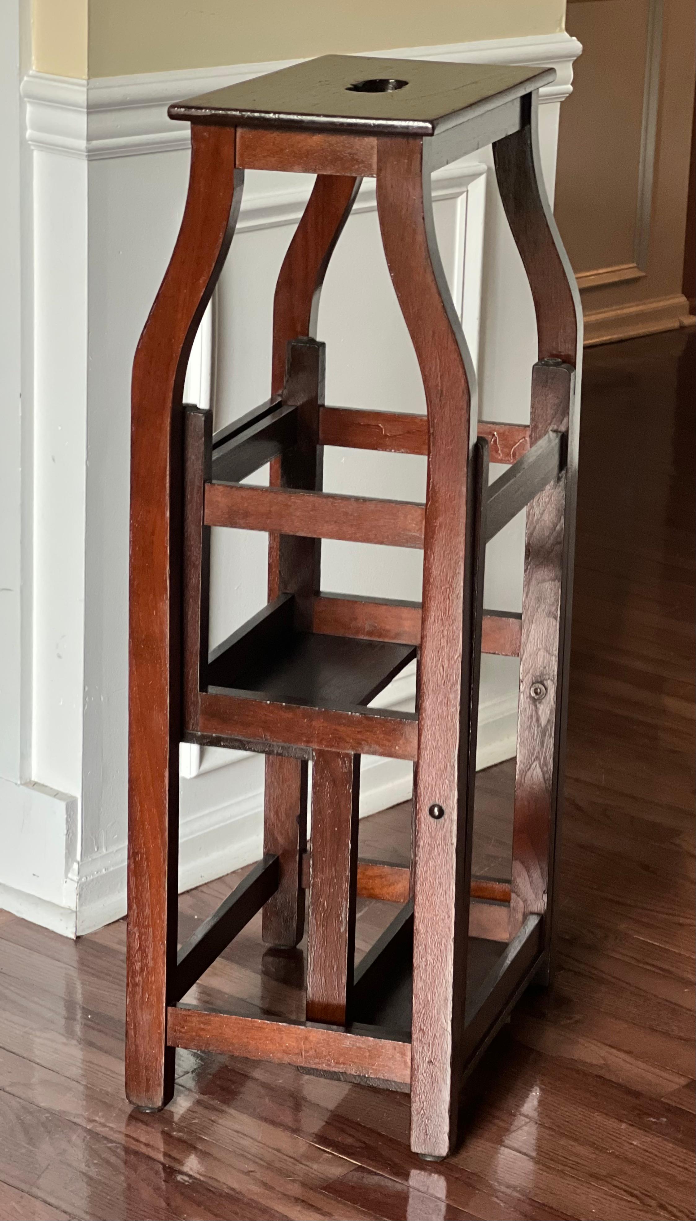19th century French oak metamorphic library ladder or step stool, France, c. 1890's.

This versatile ladder easily folds into the frame with a single, smooth pivot motion.  It features a sturdy, slender oak frame with mahogany steps and a pierced