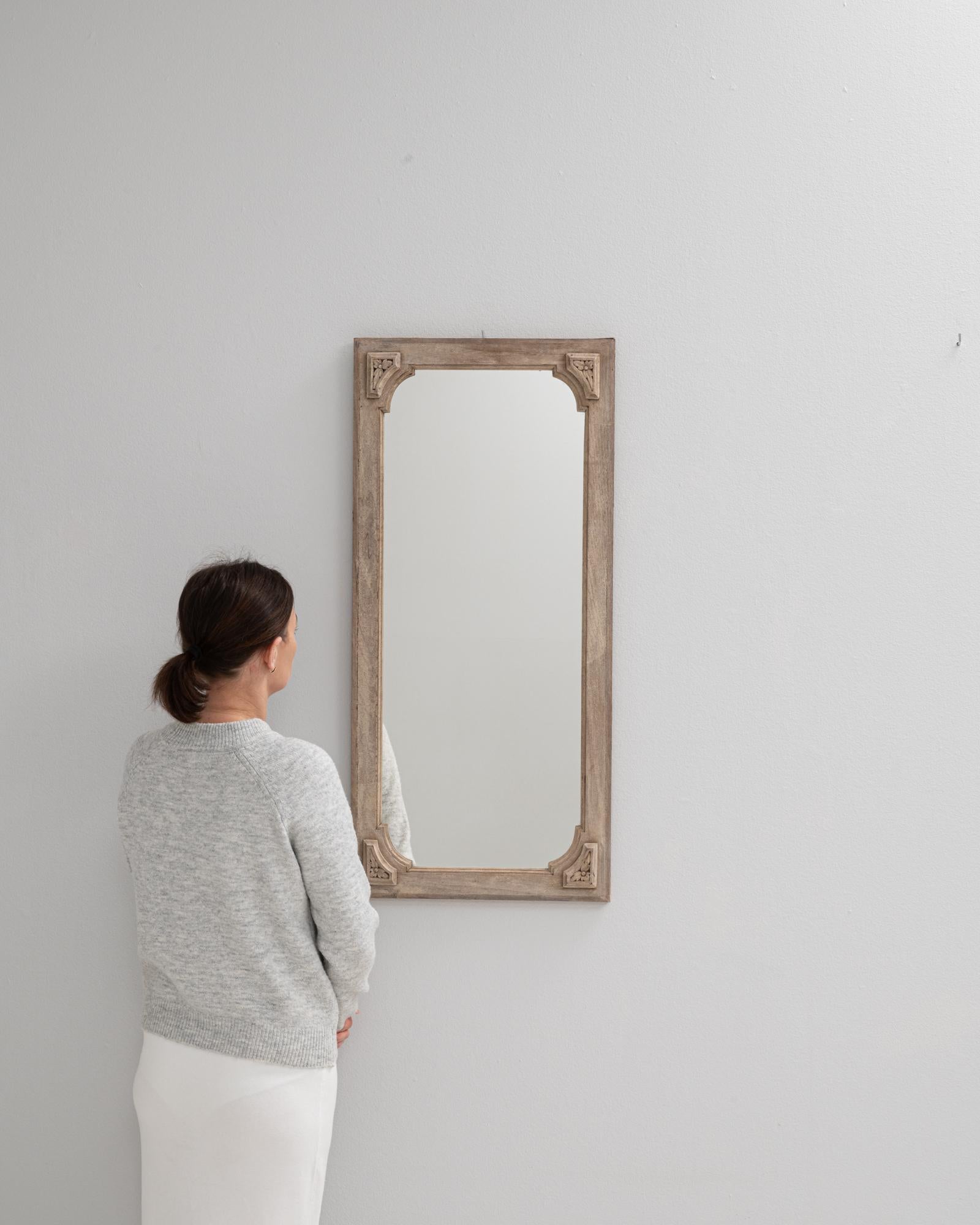 This 19th Century French oak mirror features an elegant rectangular frame accented by floral carvings in each corner. The frame’s light, weathered oak finish enhances the soft curves and bevelled details that outline the glass. Stylized corner