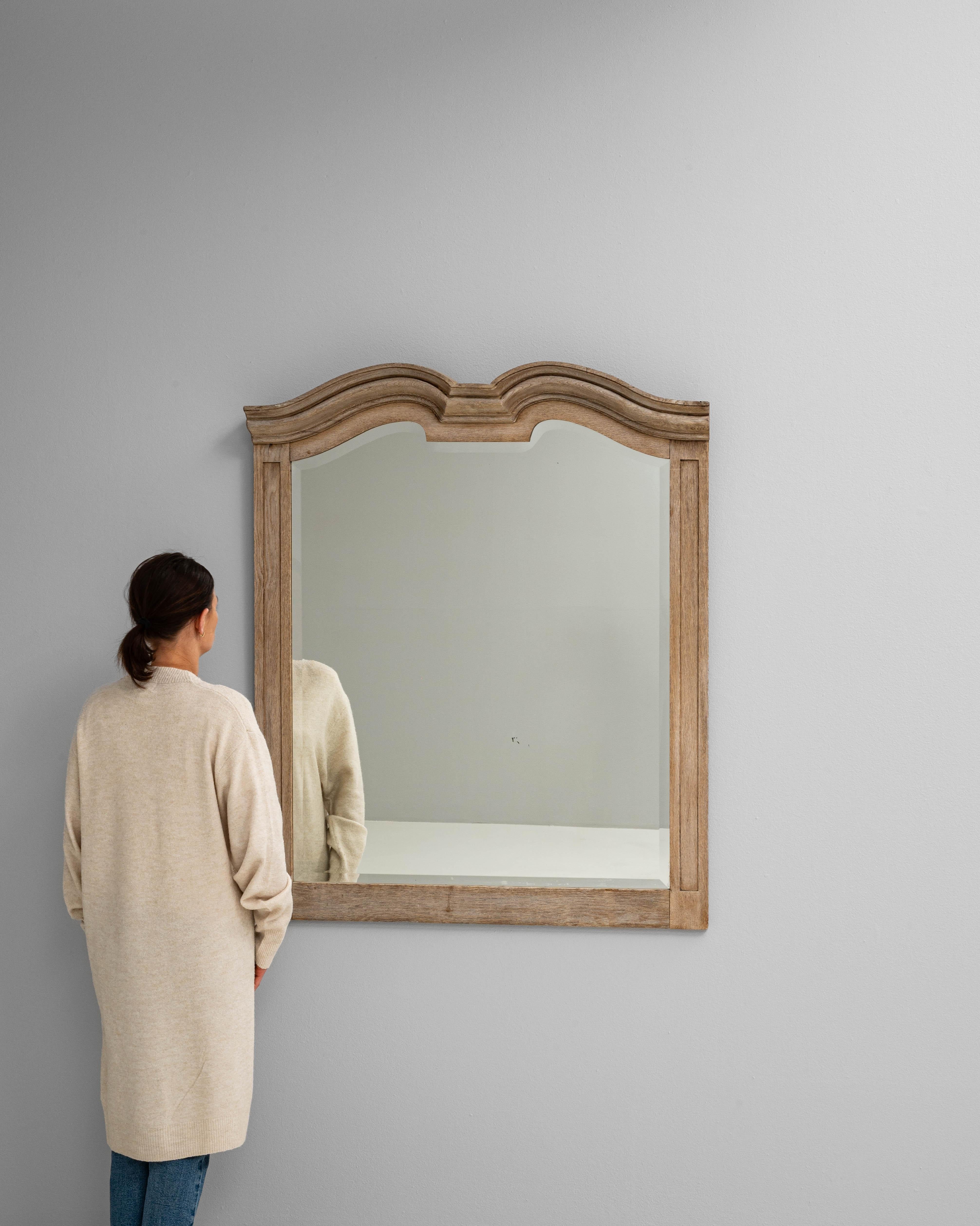 Ce miroir en chêne français du XIXe siècle présente un élégant arceau aux courbes fluides et aux moulures en escalier, caractéristiques de l'artisanat provincial de l'époque. Le cadre est fabriqué en chêne massif et conserve une patine douce et