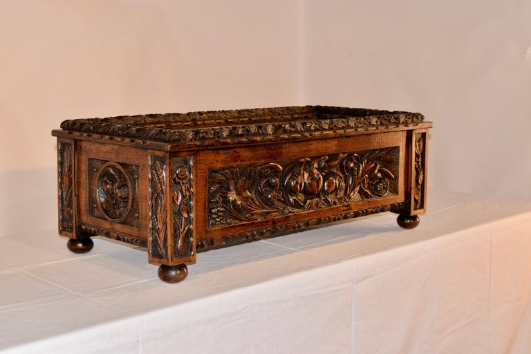 This elegant antique planter was hand made in France, circa 1870. Rectangular in shape and made of oak, the detailed jardinière stands on four hand turned feet. It is hand carved decorated on all sides and the molded border around the top as well is