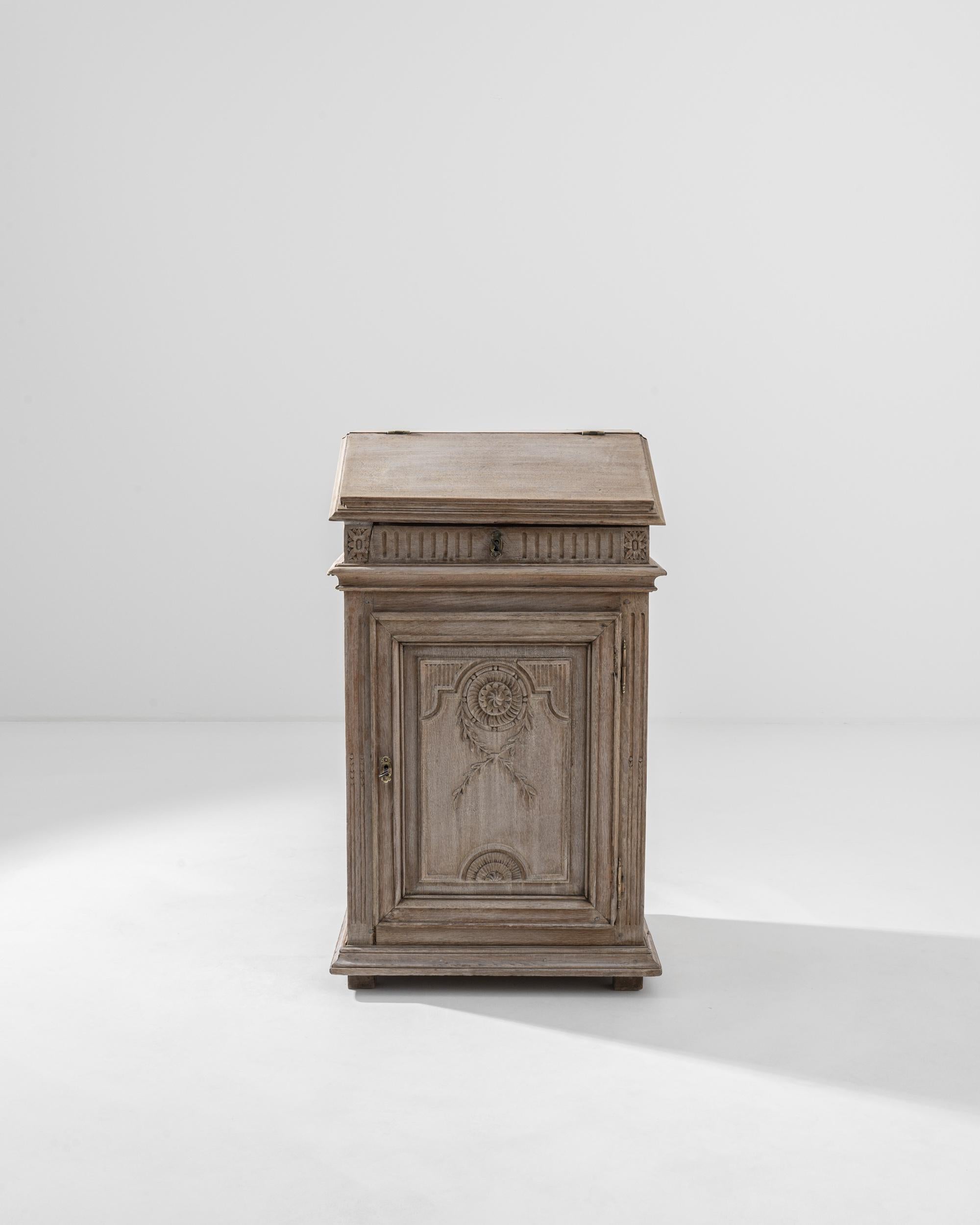A wooden desk made in 19th century, France. This tall desk has been carefully bleached so as to enhance its natural oak surface and highlight the elaborate carvings that adorn its surface– bringing new urgency to lessons from the past. A mesmerizing