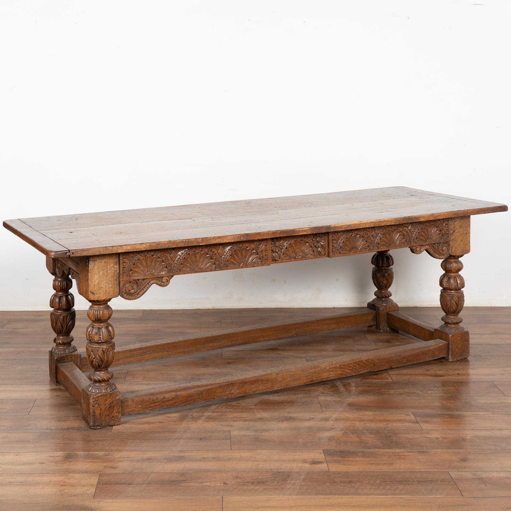 The deep patina of the aged oak wood draws one to this handsome refectory or library table from France. 
The carved, turned legs and stretcher base add to the visual appeal.
There are two carved panel drawers that add a dramatic element to this