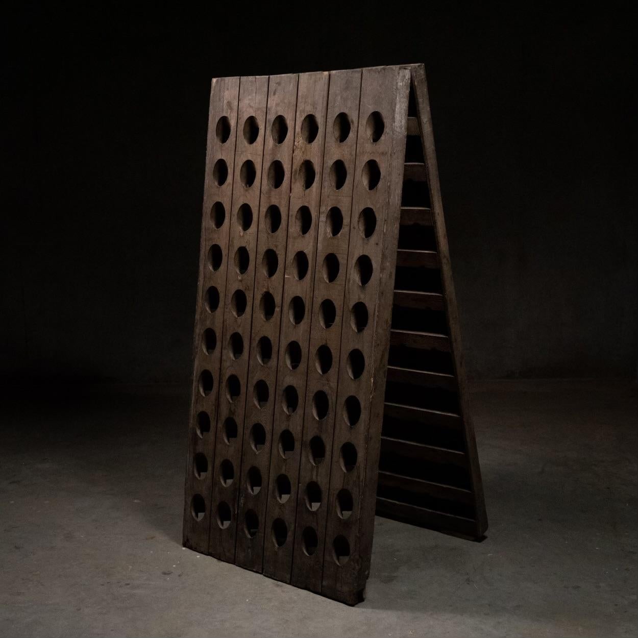 This piece is known as a Riddler rack. for bottle storage in many caves / chats in Europe.
This solid oak good patina unit is in its original folded format, but can be adjusted into two racks for wall display.
Found in USA.
