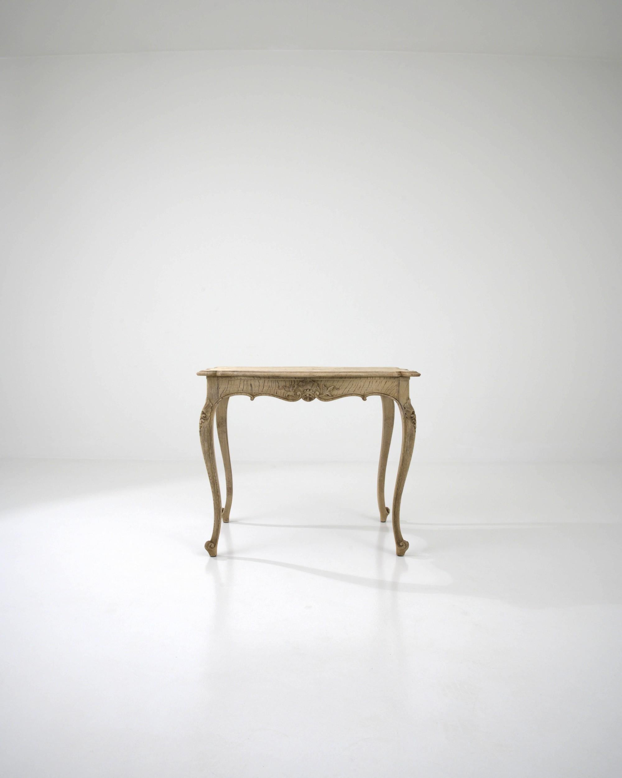 An oak side table originating in 19th Century France. This table was designed in the fashion of its time. A shell ornament indicates Rococo, the shape of the legs – a subtle cabriole – skews Baroque, the scalloped outline classical. This eclectic
