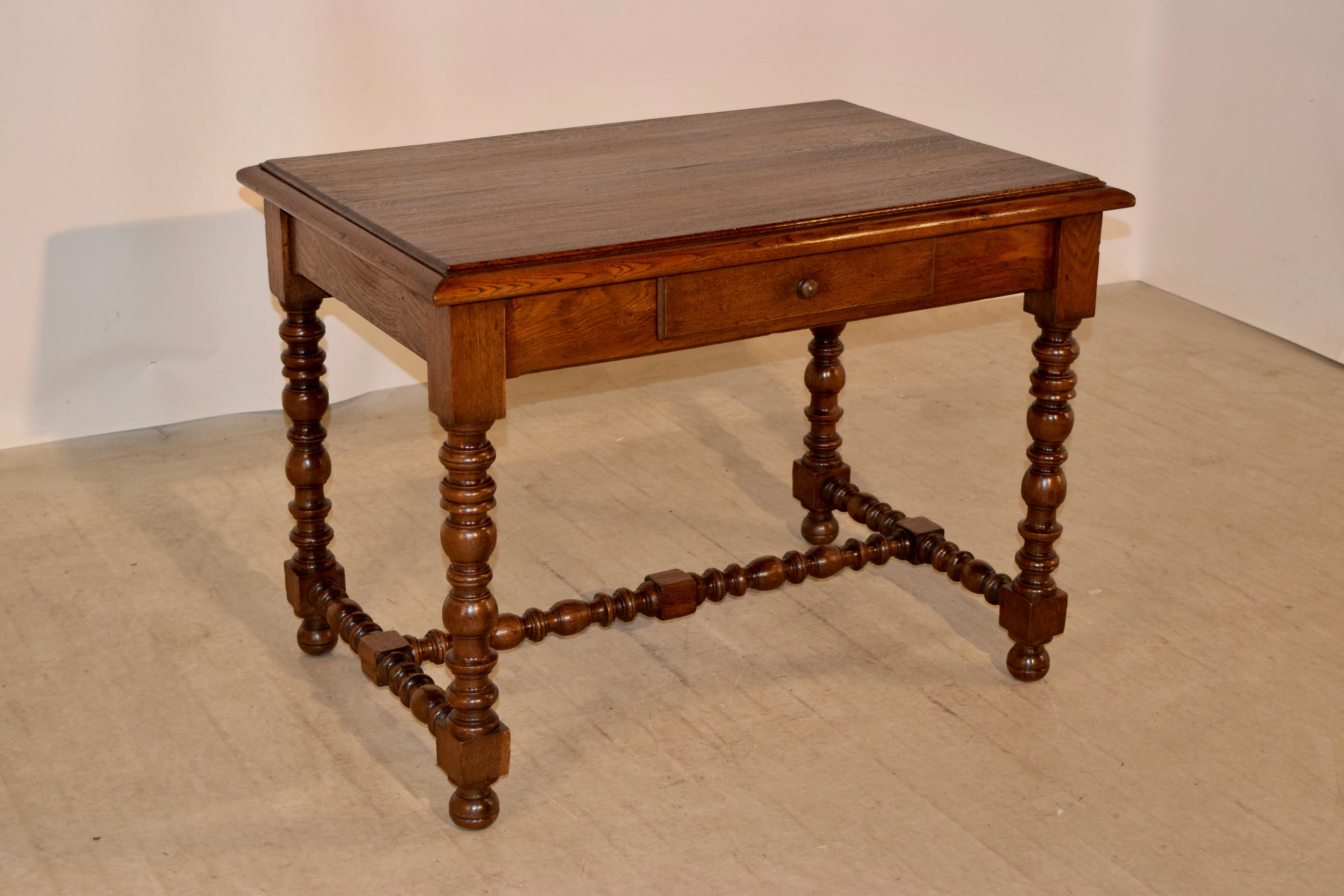 19th century oak side table from France with a beveled edge around the top following down to a simple apron which contains a single drawer in the front and the table is supported on wonderfully detailed hand-turned legs which are joined by