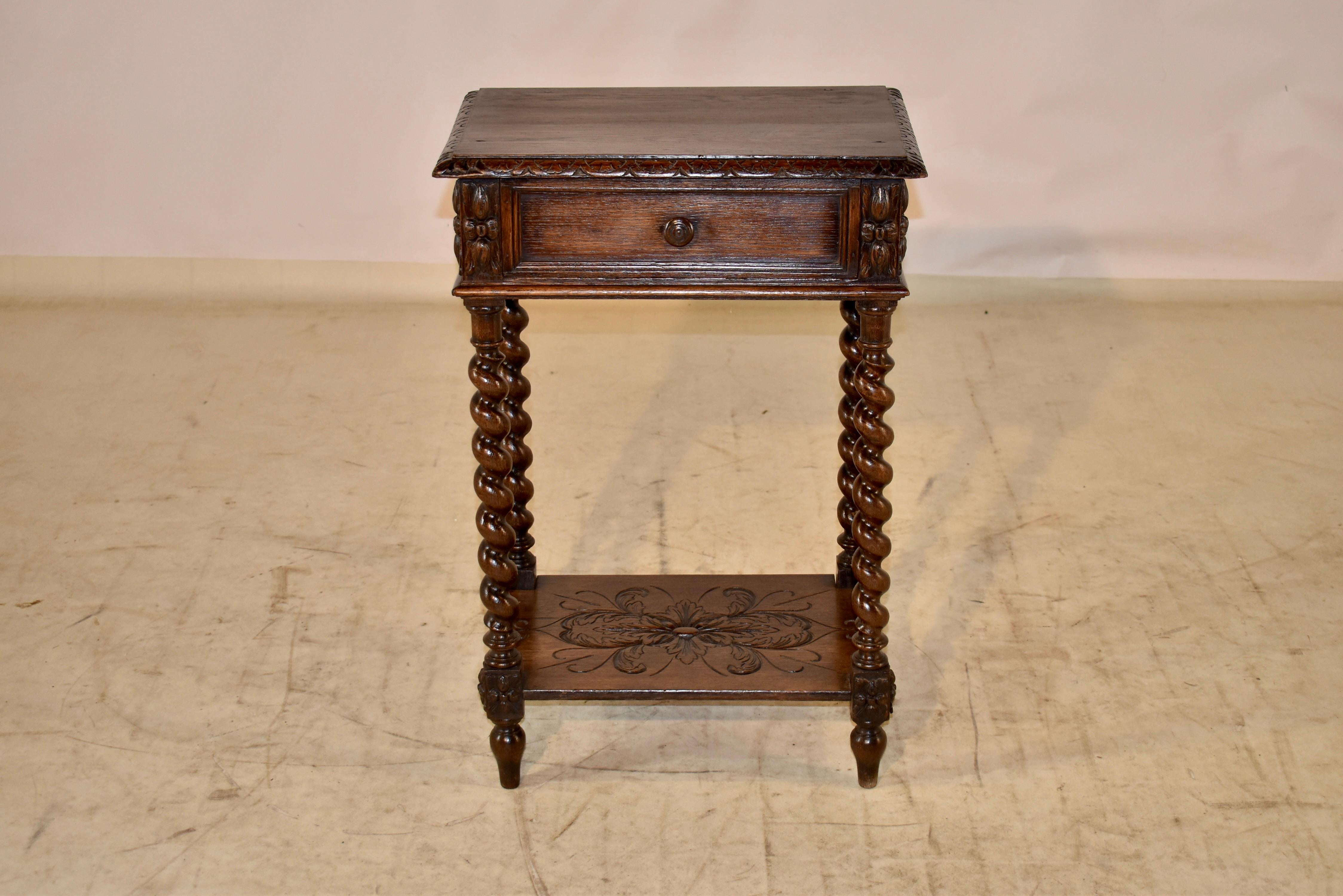 19th century oak side table from France with a wonderfully grained top which has a beveled and carved edge, following down to paneled sides, the panels flanked by applied hand carved details. There is a single paneled drawer in the front and the
