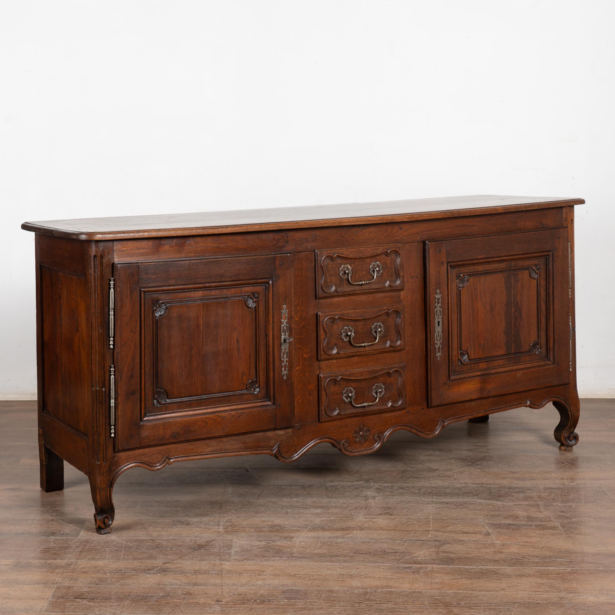 Credenza buffet in rovere francese con tre cassetti centrali affiancati da due ante a pannello con un'invitante patina profonda.  Le cerniere e i tiretti originali in ottone francese sono rimasti; le serrature possono funzionare in modo rigido (1
