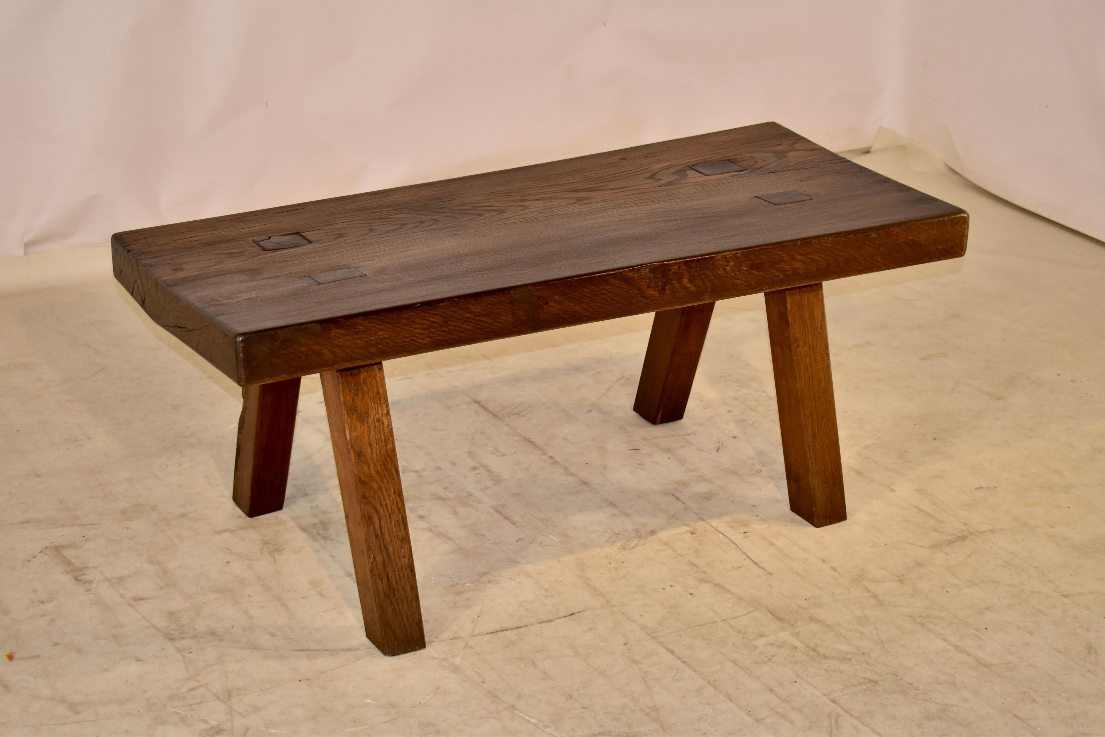 19th century oak coffee table from France with a thick 2.88 inch slab oak top. The top is fantastic and is set on four primitive block type legs, which are splayed and paged into the top. This is a lovely table that will compliment any type of decor.
