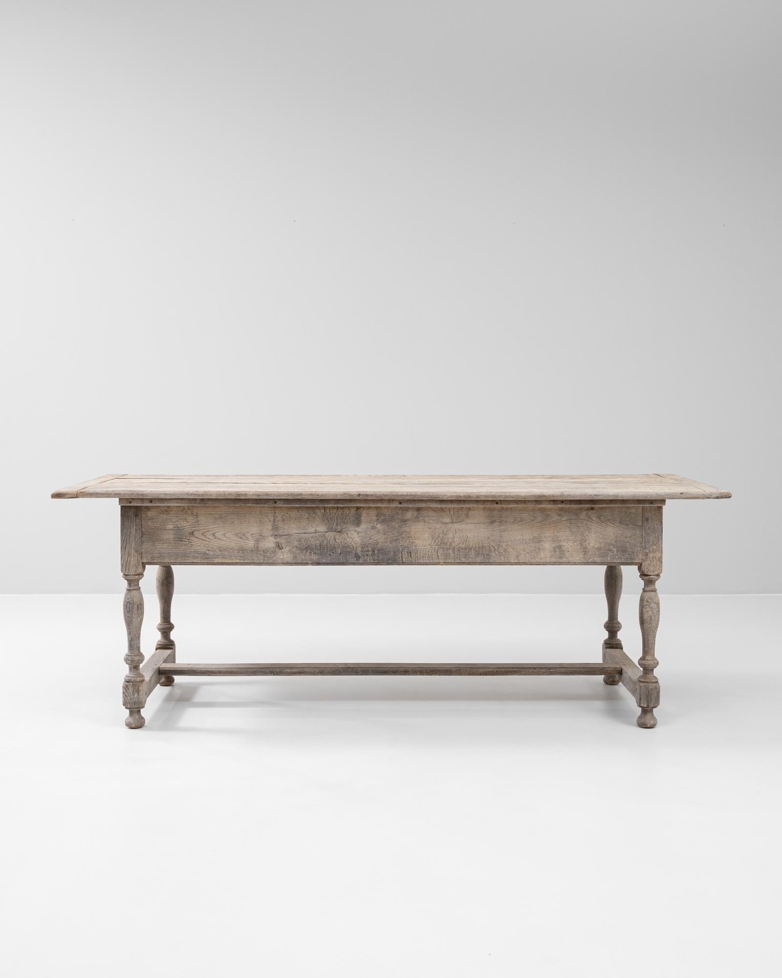 This 19th Century French oak table showcases the enduring elegance of provincial craftsmanship. Constructed from solid oak, the table features a generous rectangular top with a subtly beveled edge and warm, weathered patina that highlights the