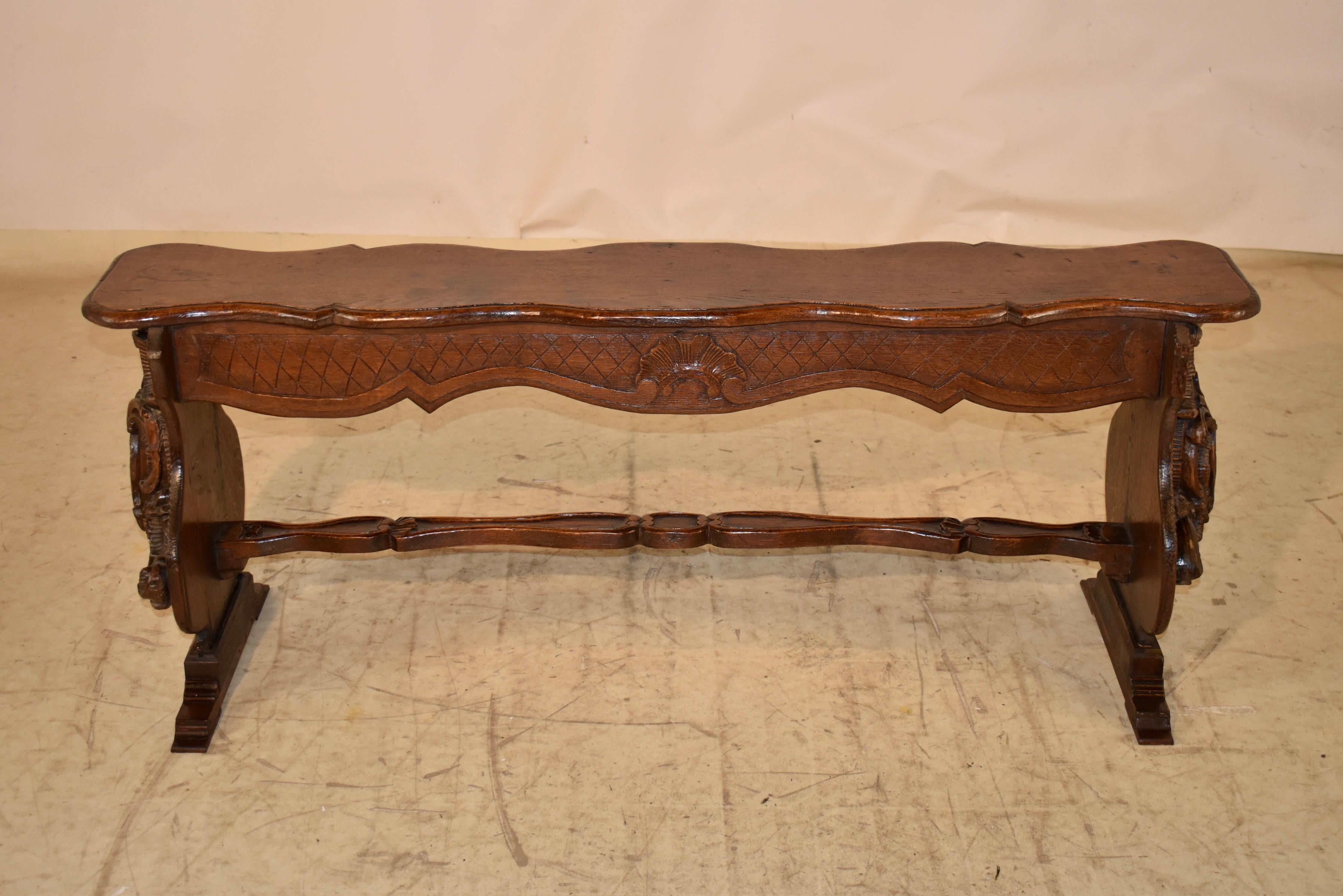 Early 19th century hand carved oak bench from France.  The seat is wonderfully scalloped and has a shaped and beveled edge, following down to a hand scalloped and carved decorated apron.  The apron is also carved on both sides of the bench for easy