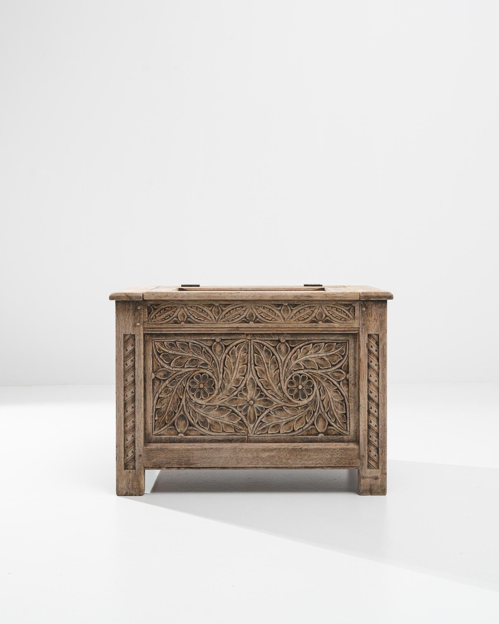 Ornate carving gives this antique oak trunk an enchanting Neo-Renaissance aesthetic. Made in France in the 1800s, the front panel of the case is carved with an intricate motif of curving leaves and petalled flowers, which fills the entire space with