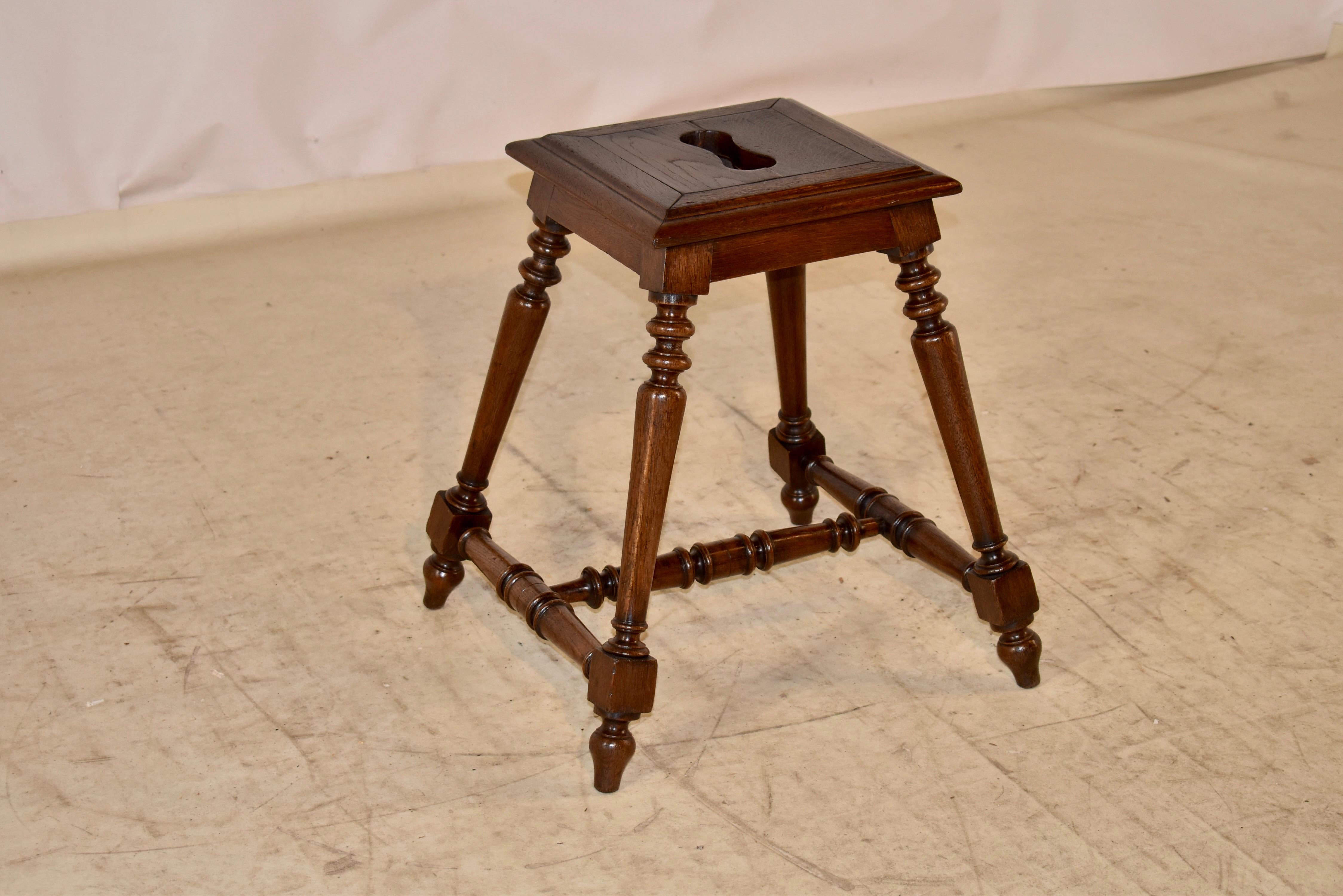 19th century oak stool from France.  The seat has a wide molded edge, surrounding a banded seat with a handle I the center for easy portability.  The seat measures 12.88 inches x 12.75 inches.  The seat is supported on splayed and hand turned legs,