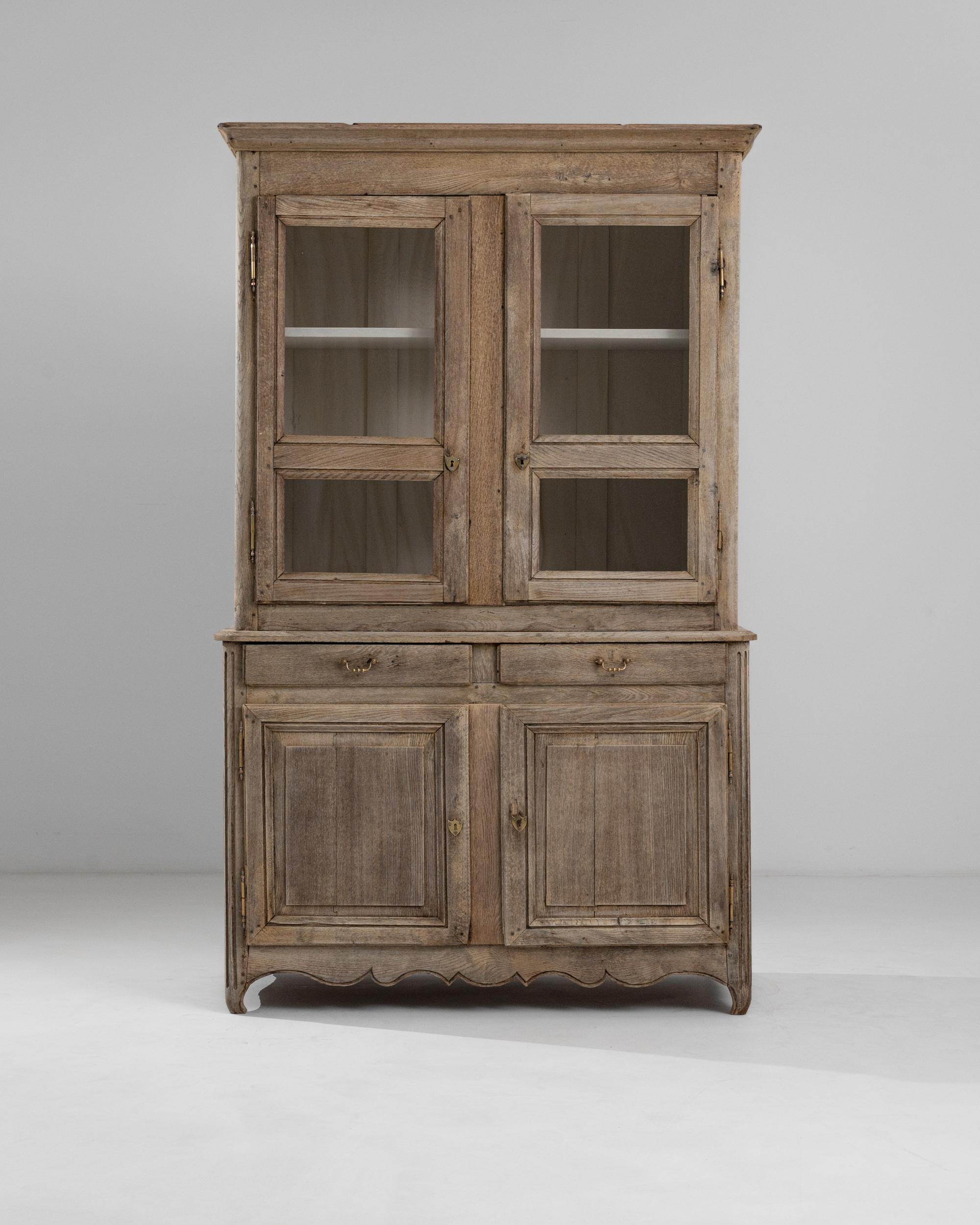This antique oak vitrine offers a slice of French provincial charm. Built in France at the beginning of the 19th century, this piece would have been a prized possession in an elegant farmhouse kitchen or rural chateau. The windows of the upper
