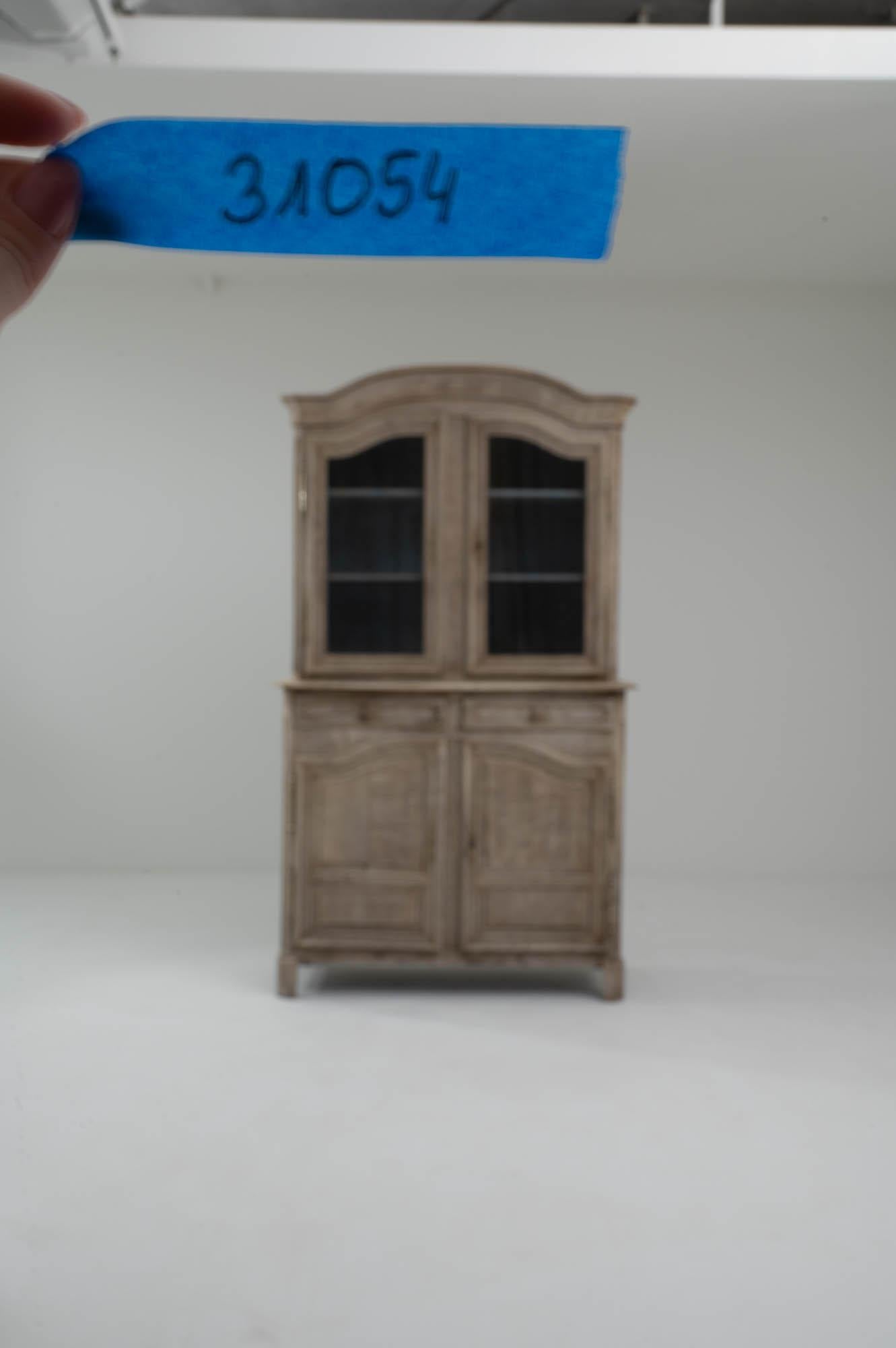 This antique Provincial vitrine in natural oak combines elegance with country simplicity. Made in France in the 1800s, the gentle arch of the cornice is echoed in the shape of the lower cupboard doors to form a harmonious composition. The windows of