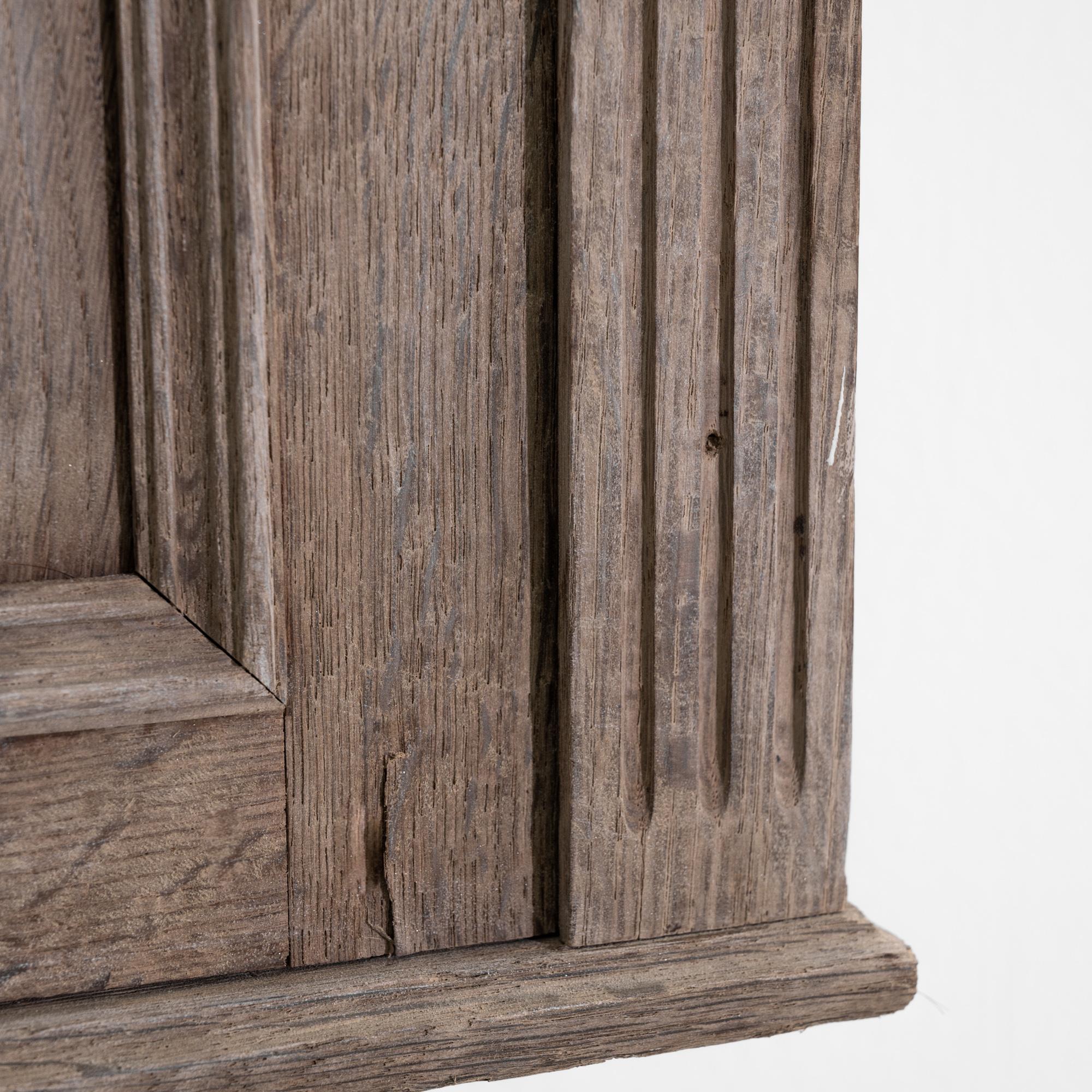 A 19th century wall cabinet from France, this antique oak cabinet sports a carved case with fluted sides, adorned with dainty finials on the top. Floral scrolls embrace a central monogram crest delineating the letters V and P interlaced, evoking a