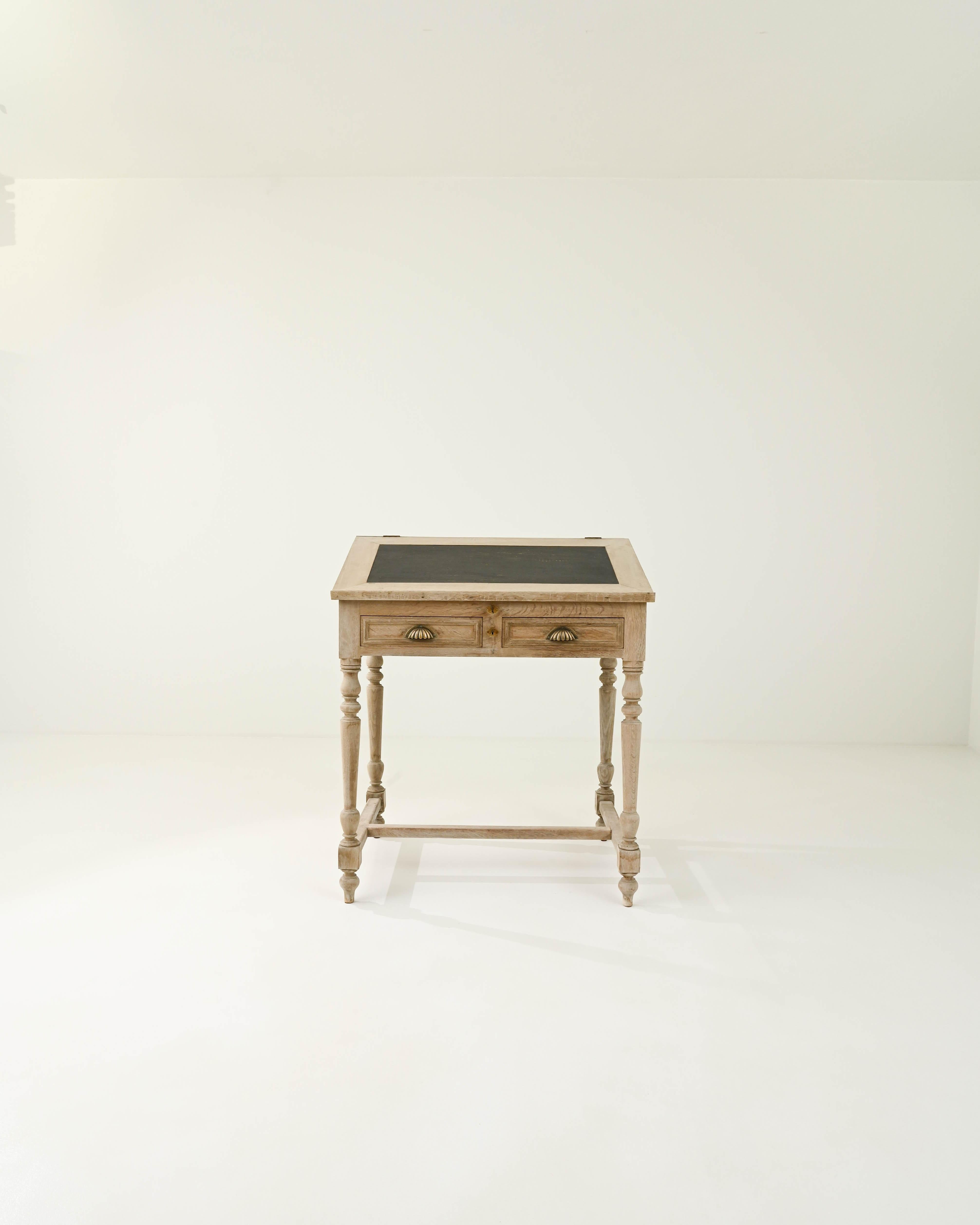 This oak desk was made in France in the 19th Century. An original concept for a standing height desk, this practical piece is designed in the elegant style of the 1800s. Lathed legs and scalloped brass drawer pulls give a formal feel, while the