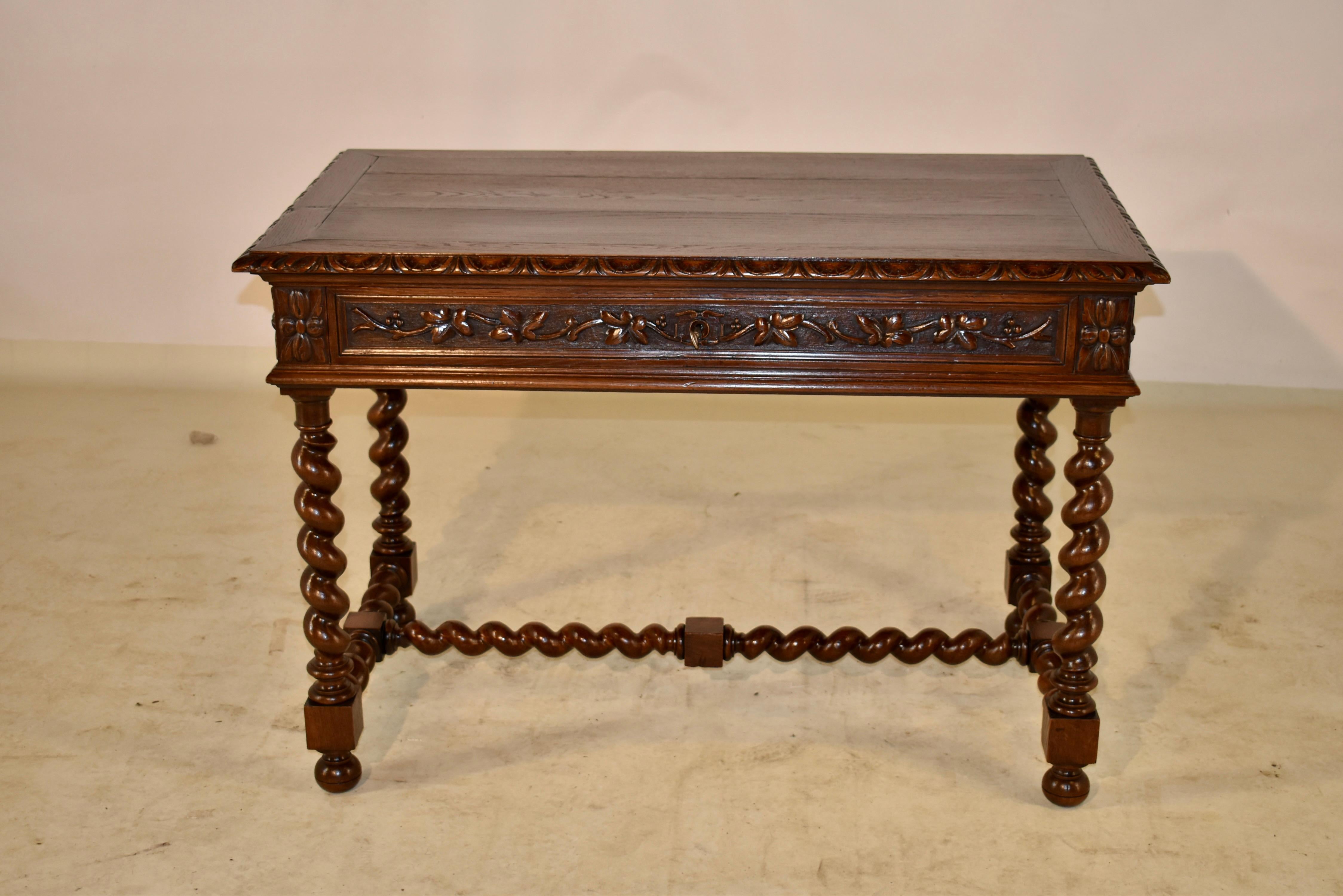 19th century oak writing or side table from France with a beveled and hand carved decorated edge around the top. The apron is hand raised paneled on all four sides , and has a single drawer in the front with wonderful hand carved leaves. The