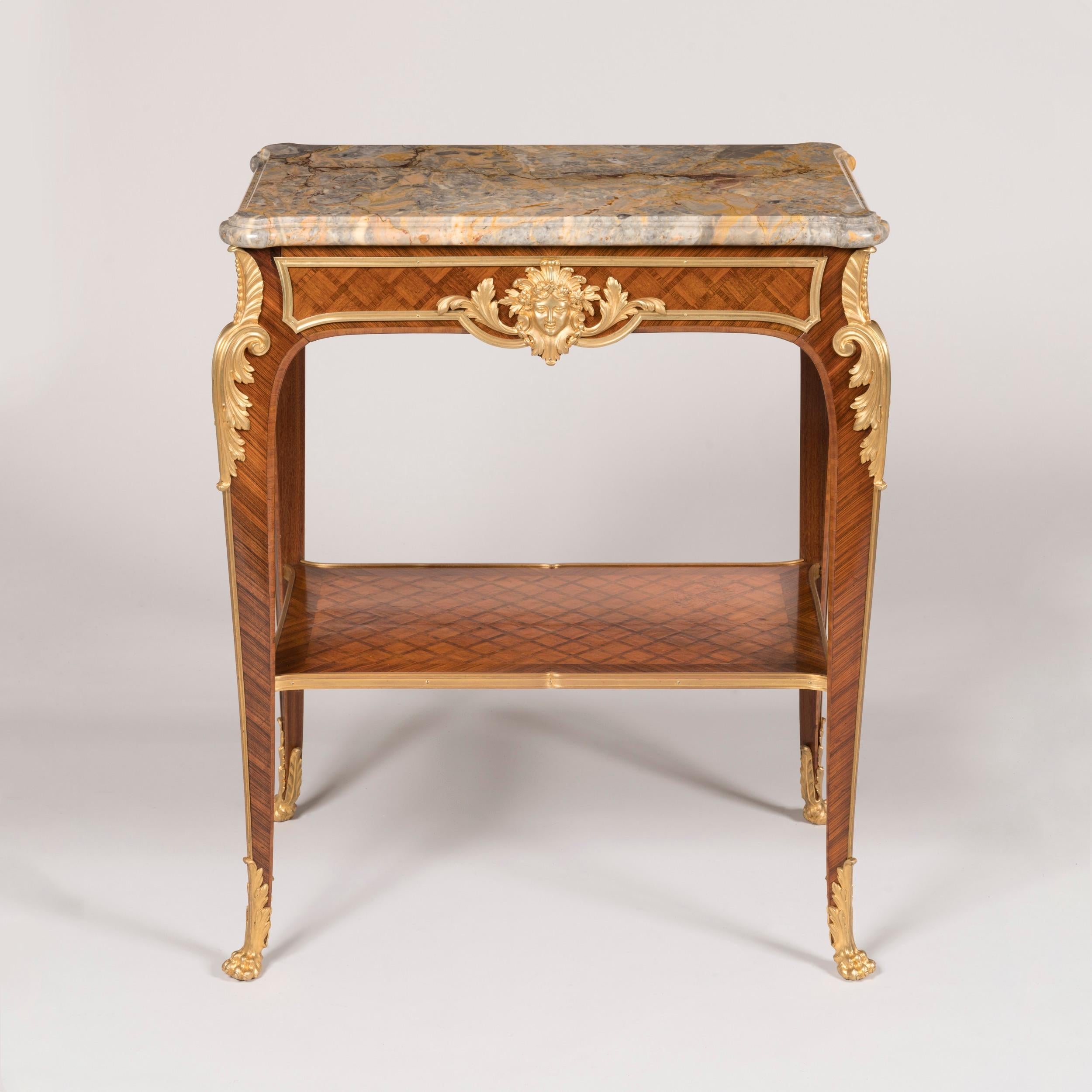 A Louis XVI Style Parquetry occasional table

Constructed in Kingwood and Tulipwood with fine ormolu bronze mounts; of free-standing form, the ormolu sabot-shod feet modelled as lions' paws, swept cabriole legs dressed with acanthus- and