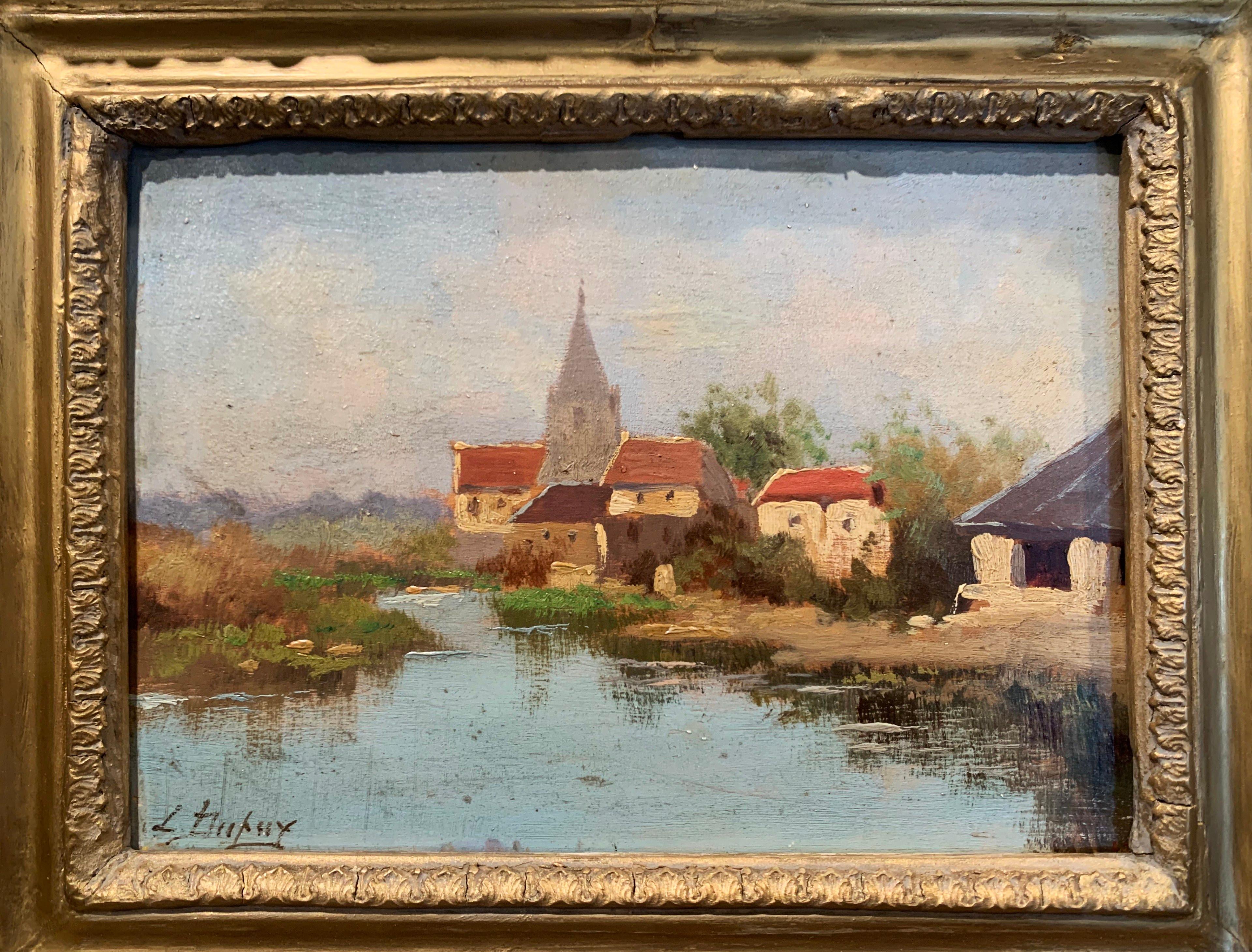 This 19th century impressionist painting was crafted in France, circa 1890. Set in the original carved giltwood frame, the artwork painted on board, illustrates a picturesque, countryside landscape scene with a church, farmhouses and a pond in the