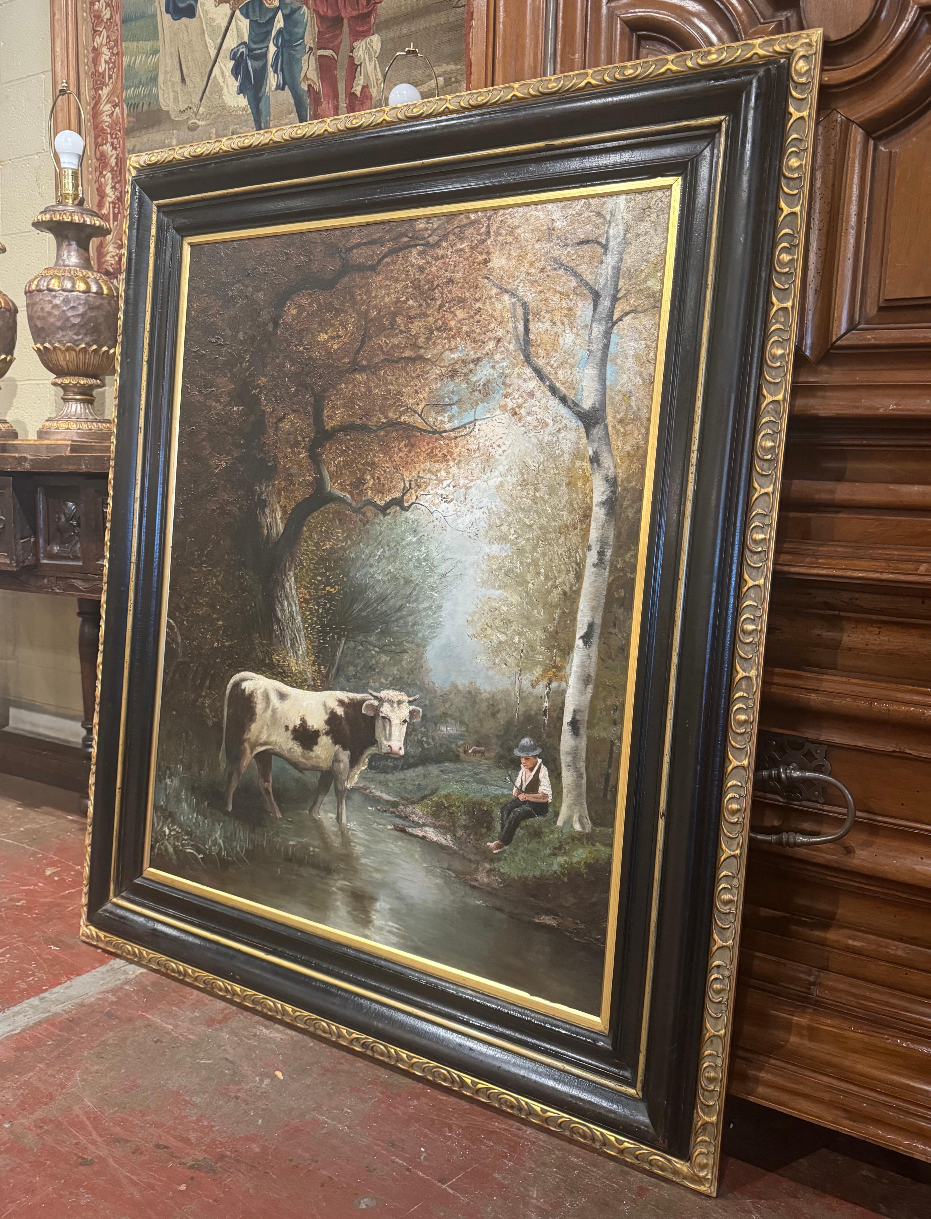 Decora un estudio o despacho con este gran cuadro antiguo de una vaca. Pintado a mano en Francia hacia 1860 y colocado en el marco original de madera tallada ennegrecida y dorada, el cuadro sobre lienzo representa una serena escena pastoral,
