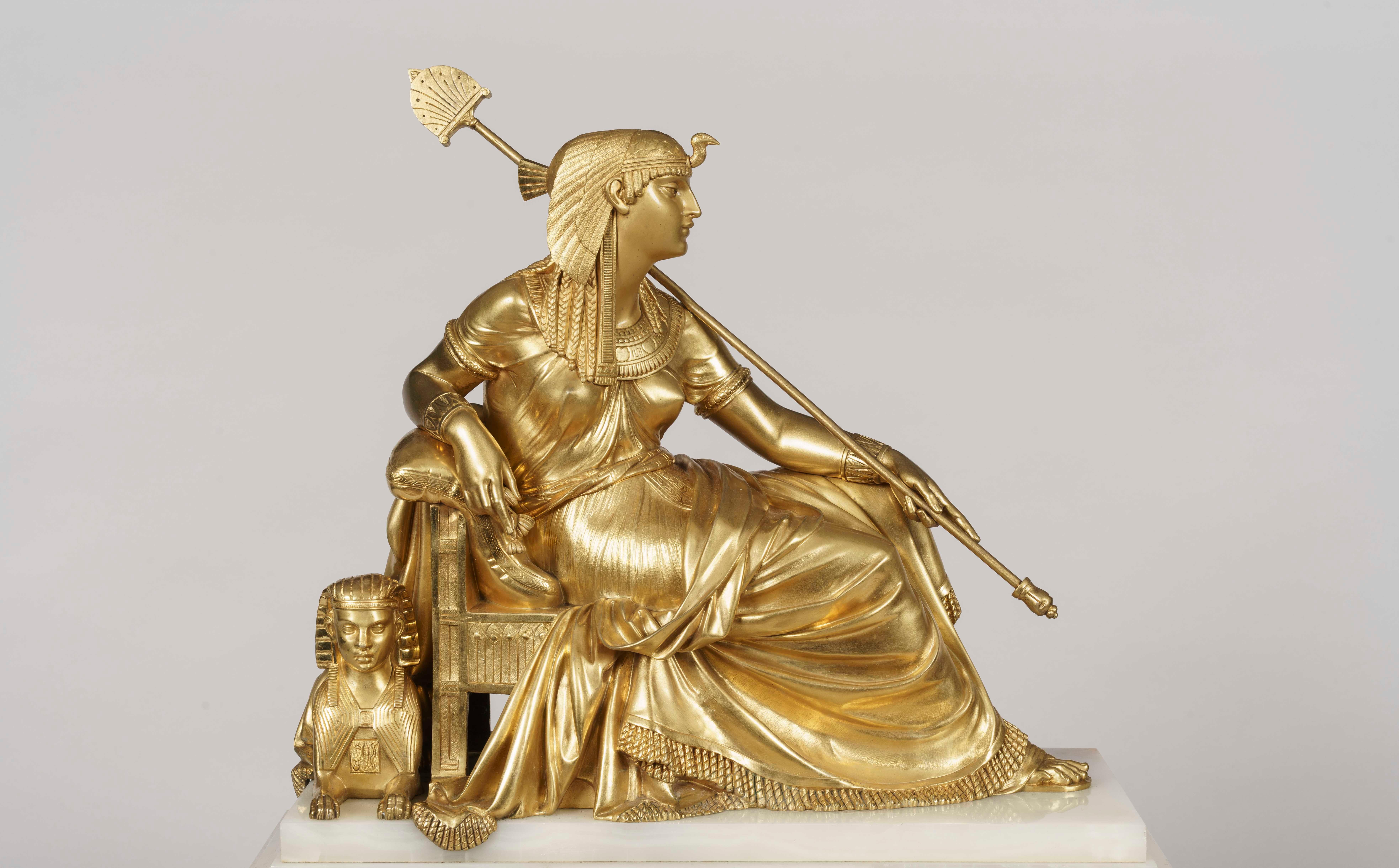 Una guarnitura di camini alla maniera egiziana

Costruito in onice algerino e ormolu, comprende un grande orologio e due pezzi laterali; si erge da piedi ad artiglio alati, la cassa dell'orologio con fronte a strappo e bordi figurati in ormolu a