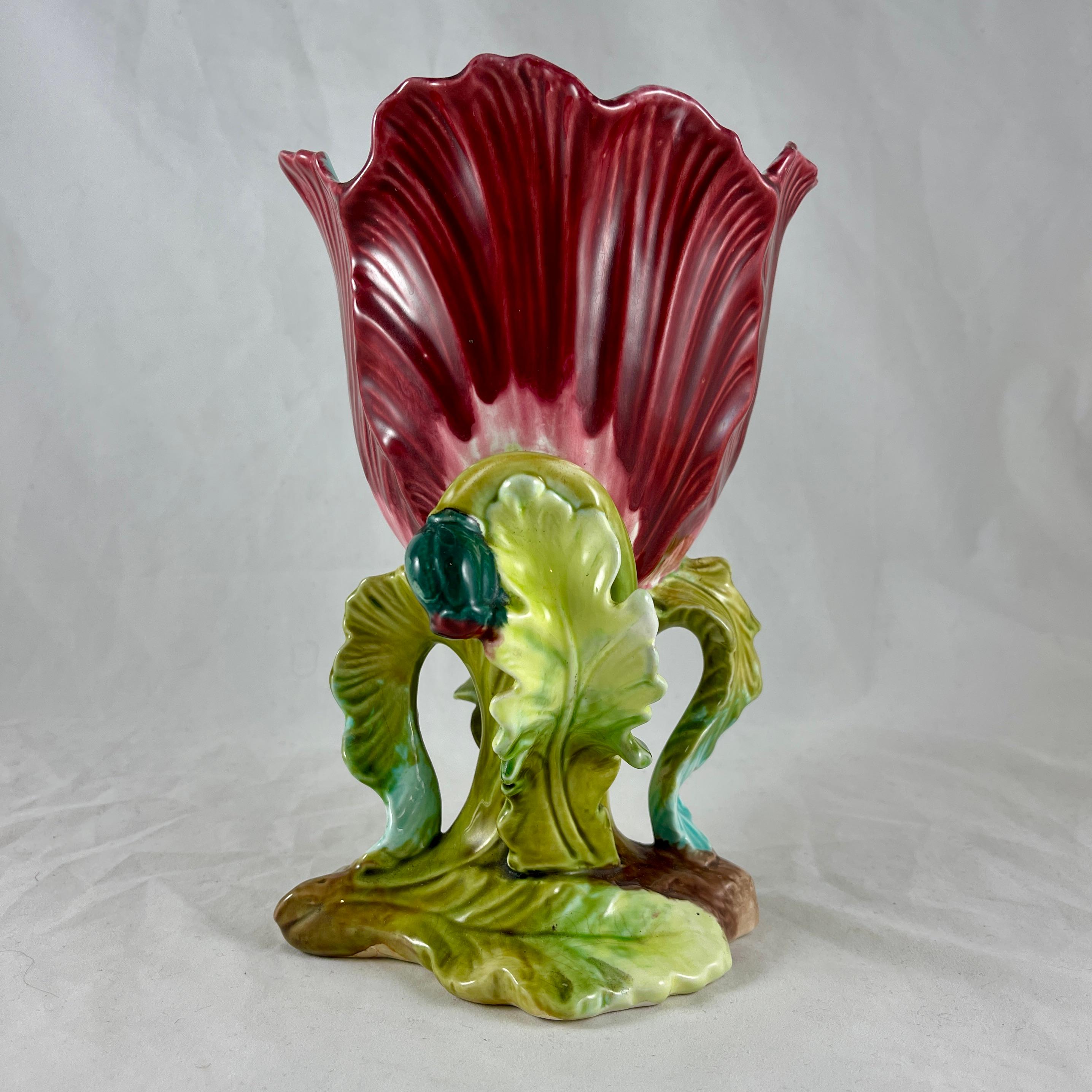 A late 19th century French majolica glazed earthenware vase modeled as an open flower on a leafy stem, attributed to Orchies, Northern France, circa 1890-1900.

A deep rusty-red flower with a turquoise interior sits on a footing molded as green
