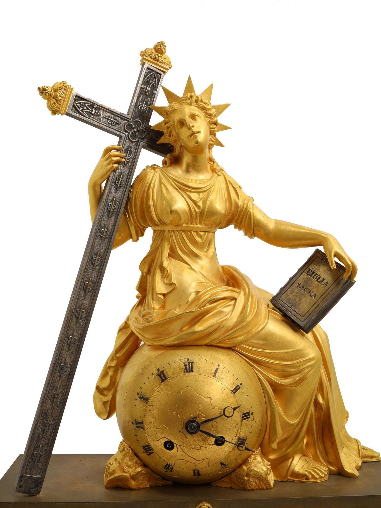 Our large French gilt and patinated bronze mantel clock dating from the second quarter of the nineteenth century  features the finest casting and gilded details.  It depicts Mary seated upon a sphere representing the globe, supporting a large cross