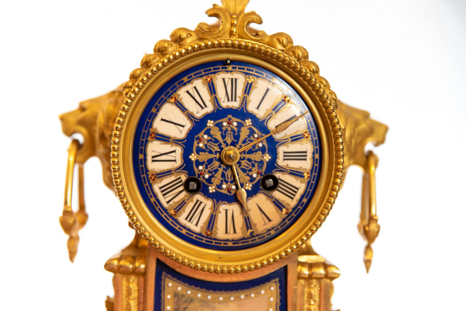 A late 19th century French Ormolu clock striking the hours and half hours on a single bell with gilding, dark blue and white porcelain dial. The case with urn shaped finial, lion mask ring drop handles, standing on scroll supports with guided