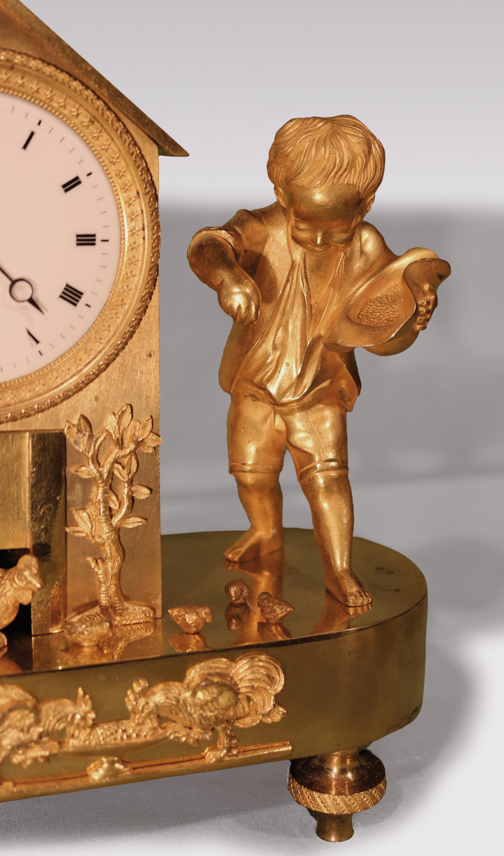 An early 19th century French ormolu mantel clock, having 8-day movement with enamel dial, mounted in “hen house” with urn and flower mounts to side, the oval base having hen and chicks being fed grain from the hat of a young boy, supported on engine