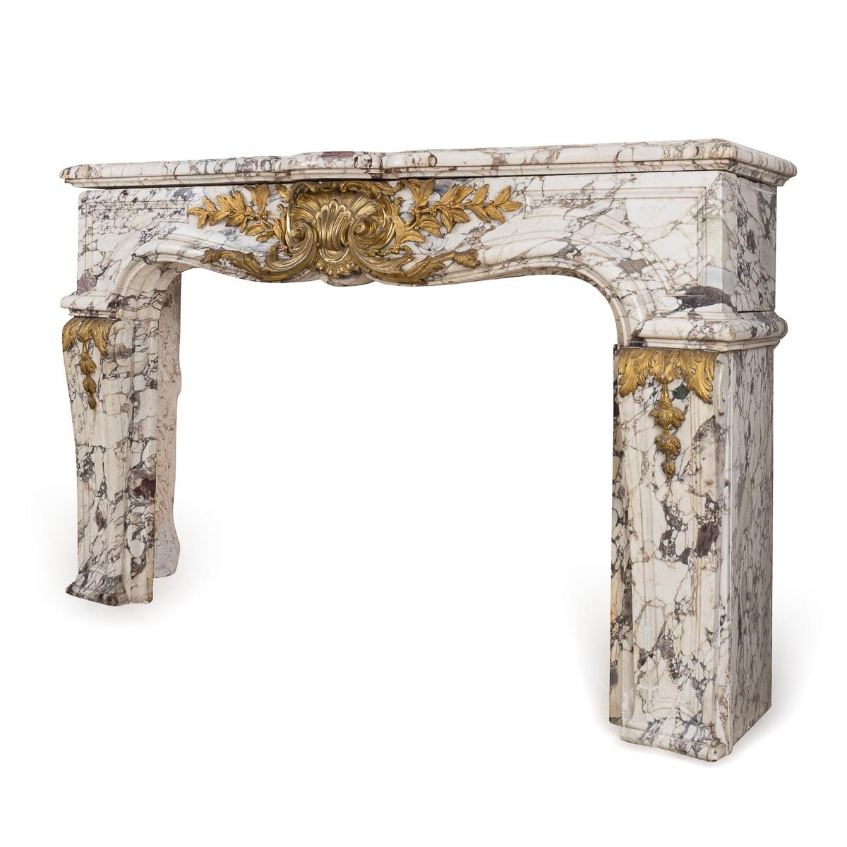 A mid 19th century French Louis XV style fireplace in Breche Violette marble. The curved shaped, stop-fluted jambs surmounted by ormolu mounted carved paterae, frieze and moulded shelf. This superb fireplace adds elegance and sophistication to any