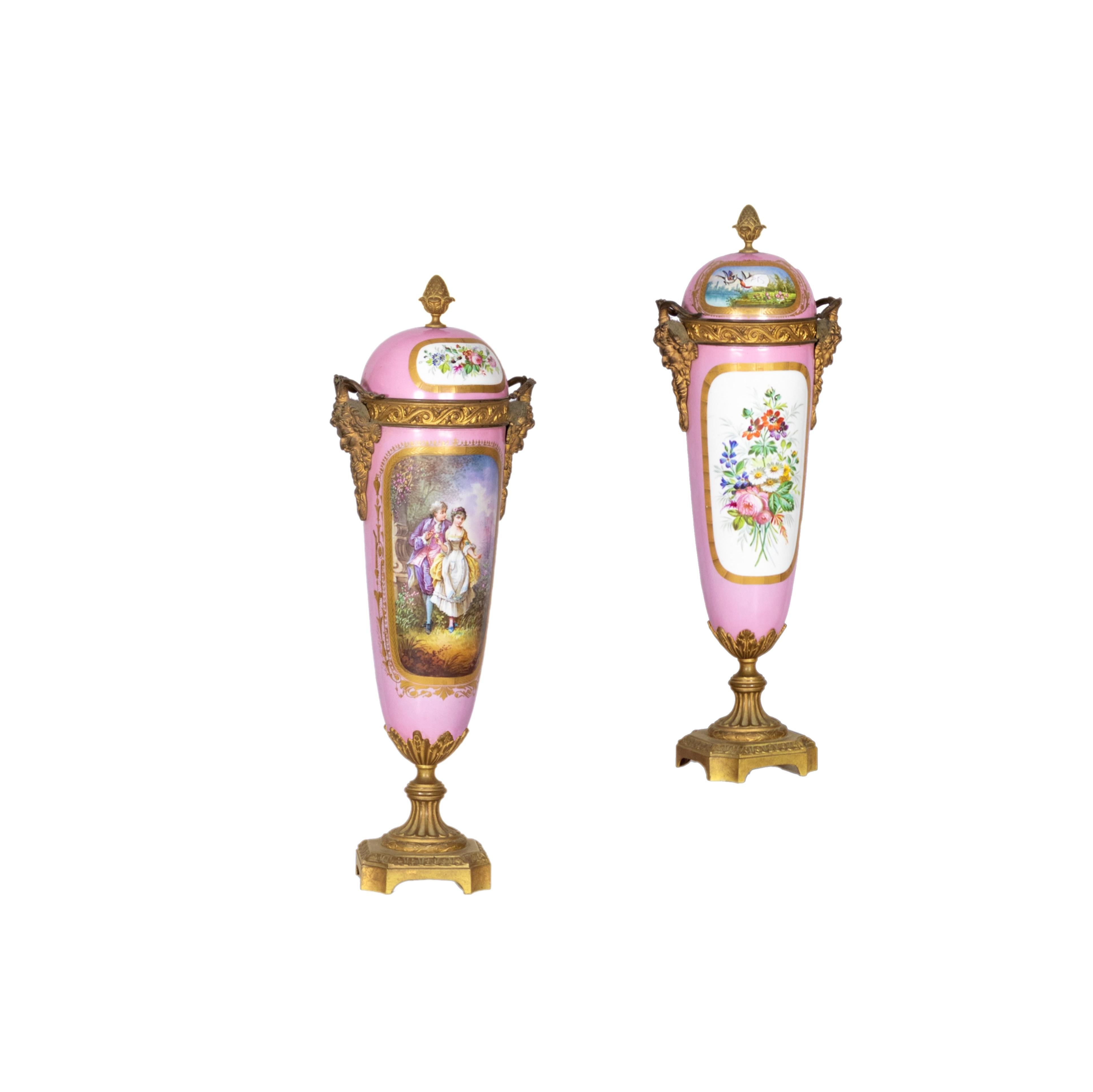A beautiful antique decorative pink porcelain Sèvres urn with a hand-painted background of a lovers scene. 

In the back there is a scene of a bouquet of flowers. Mounted Bacchus/ Dionysus bronze mask handles on the sides. ‘A Daret’ signature on the