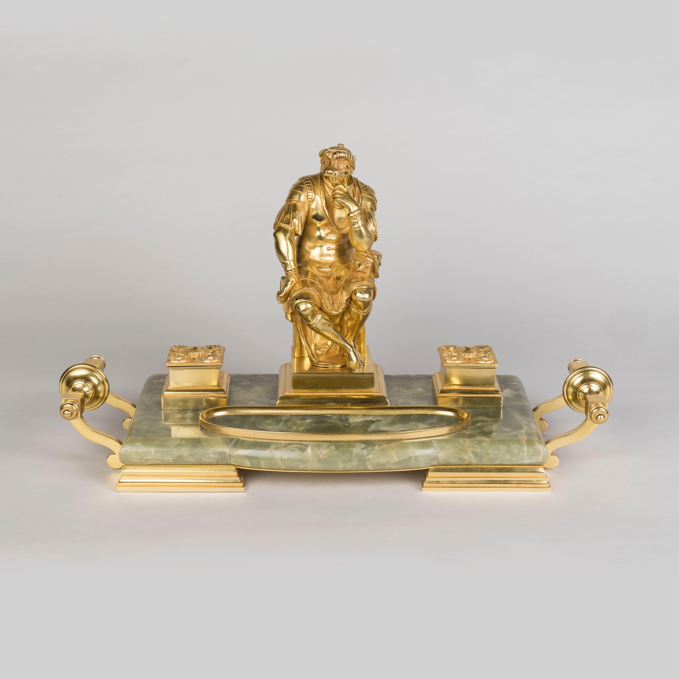 A Fine Gilt Bronze and Onyx Inkwell
Surmounted by Michelangelo's Lorenzo de Medici

Constructed from a dished piece of onyx, raised on ormolu stepped feet with carrying handles to the sides, having two lidded inkwells flanking a central figure of