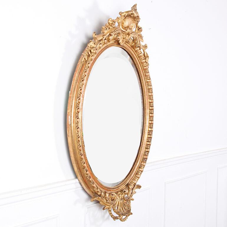 A 19th century French oval carved gilt mirror with original beveled glass and a mellow original patina to the gold leaf frame. 

  
