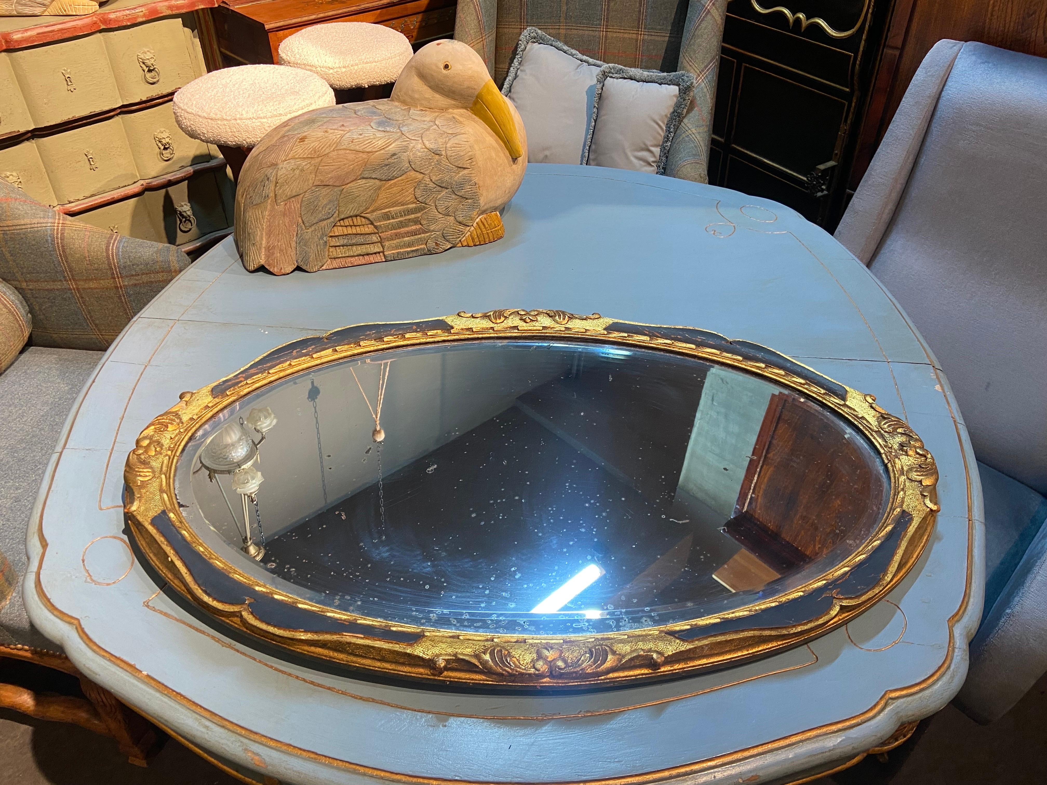 French wall mirror made in late 19th century. It has an oval shape with gilt wood symmetrical floral decorations and may be used vertically or horizontally. Still wears its original glass which is not in very good condition and could be replaced.