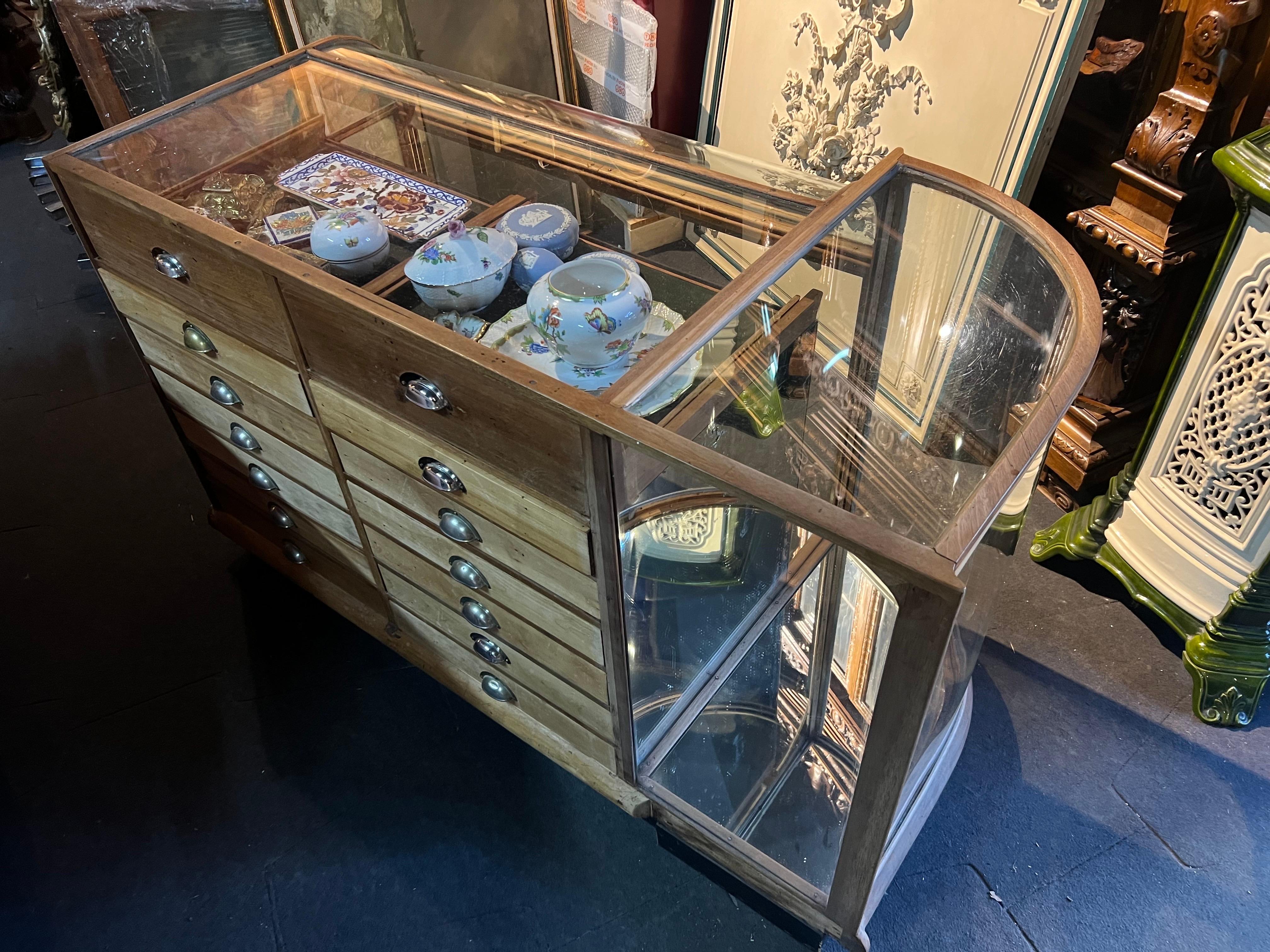 French jewellery oval vitrine made of mahogany frame with original glass parts. There are two sliding glass doors in front and a corner oval door at the left side to present bigger items and there are fourteen drawers at the back side. Top two