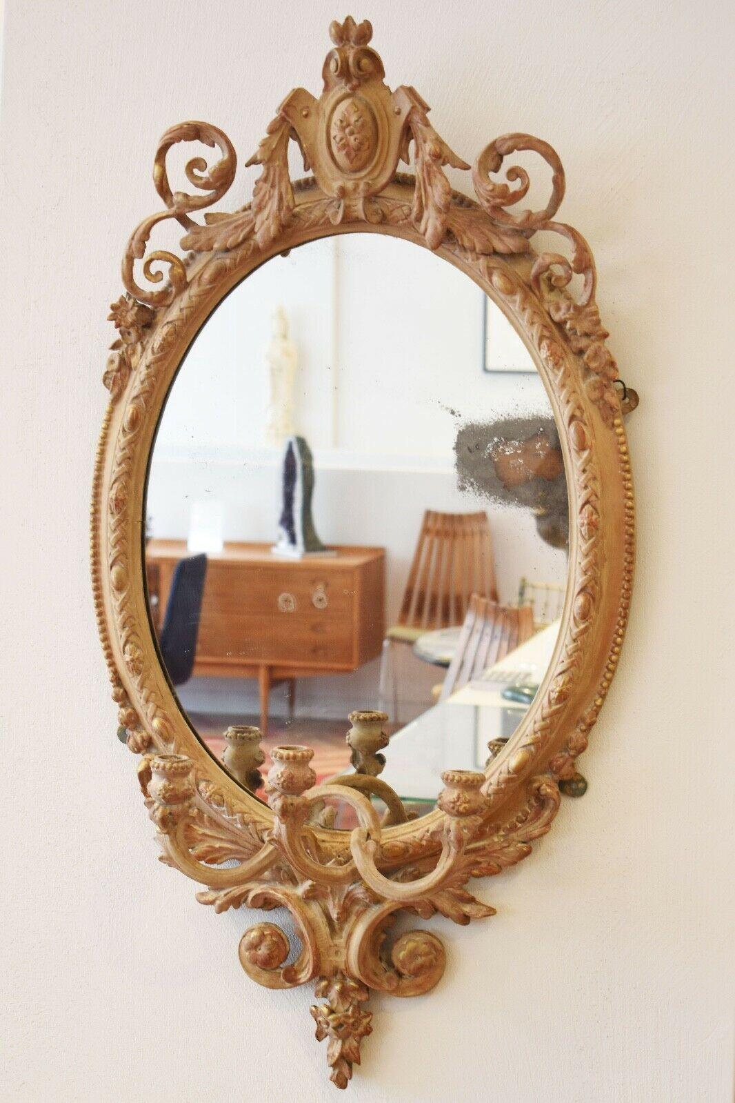 A beautiful decorative hand carved wooden oval mirror with candlestick sconces 
finished with strengthened gesso and surfaced with gold gilt.
A prime example of this technique produced in France in the late 19th Century.


 