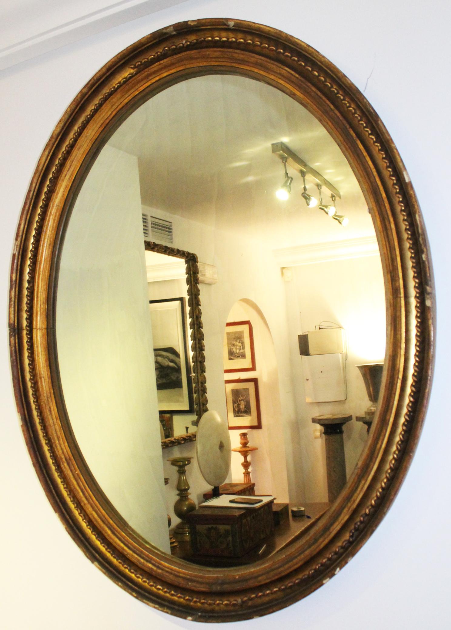 19th century French oval mirror gilded with gold leaf.