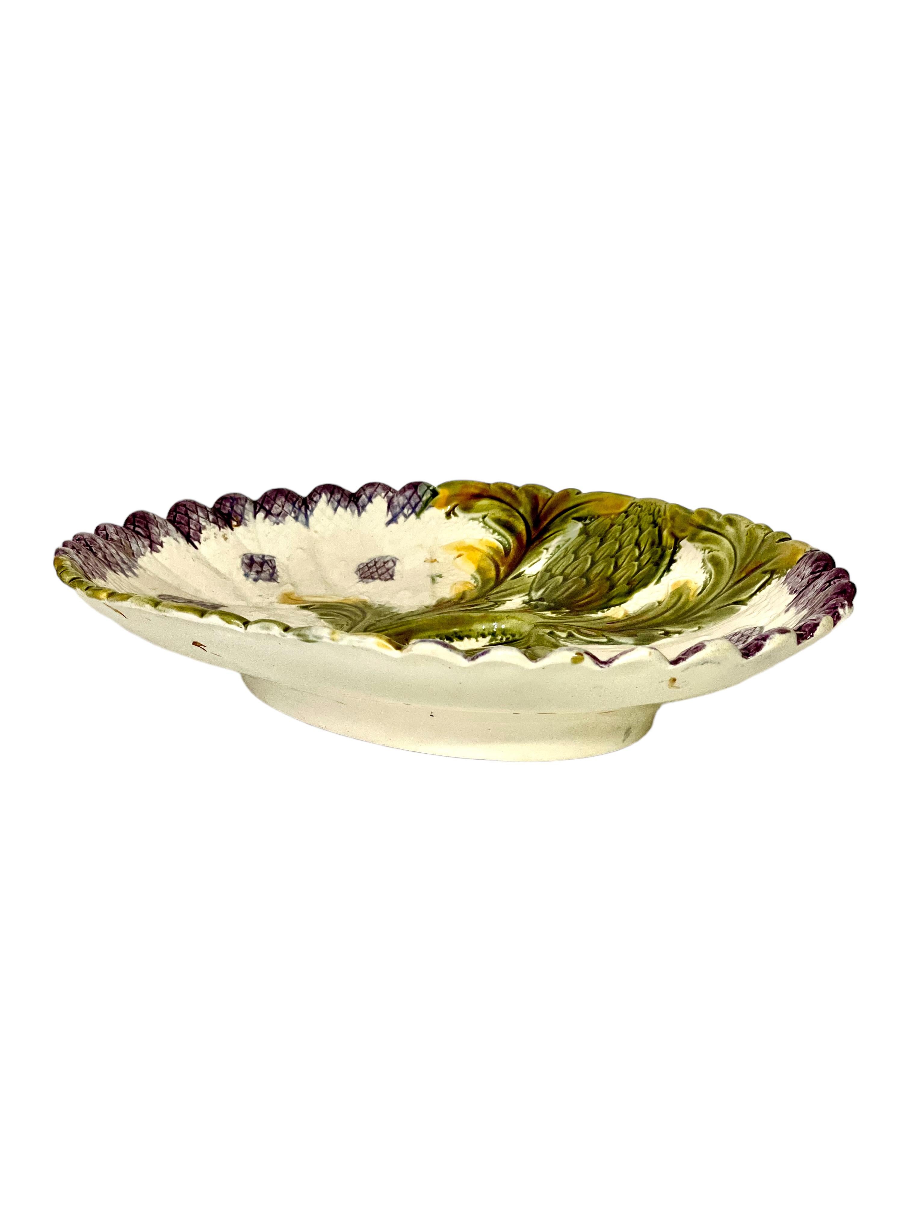 A very unusual and beautiful French barbotine majolica asparagus serving platter, oval in shape and featuring a typical 'trompe l'oeil' textured decoration of globe artichokes and purple asparagus tips, artfully entwined with each other to create a