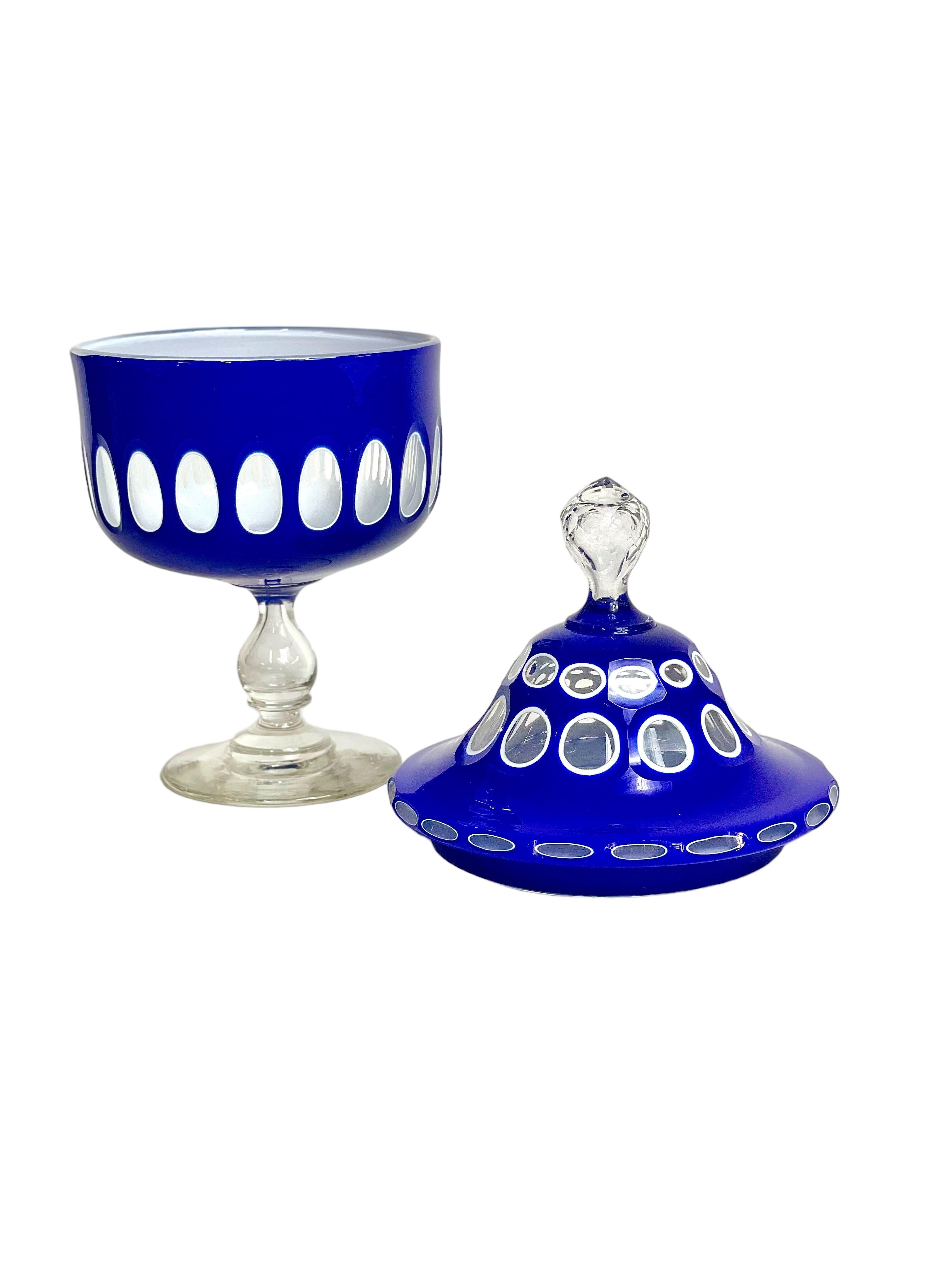 An unusual cobalt-blue or Overlay crystal ‘drageoir’ (sweet jar), with clear pedestal and fitted lid. Dating from around the 19th century, this quirky cut-to-clear overlaid container, decorated all round with clear cut-out circular windows, would