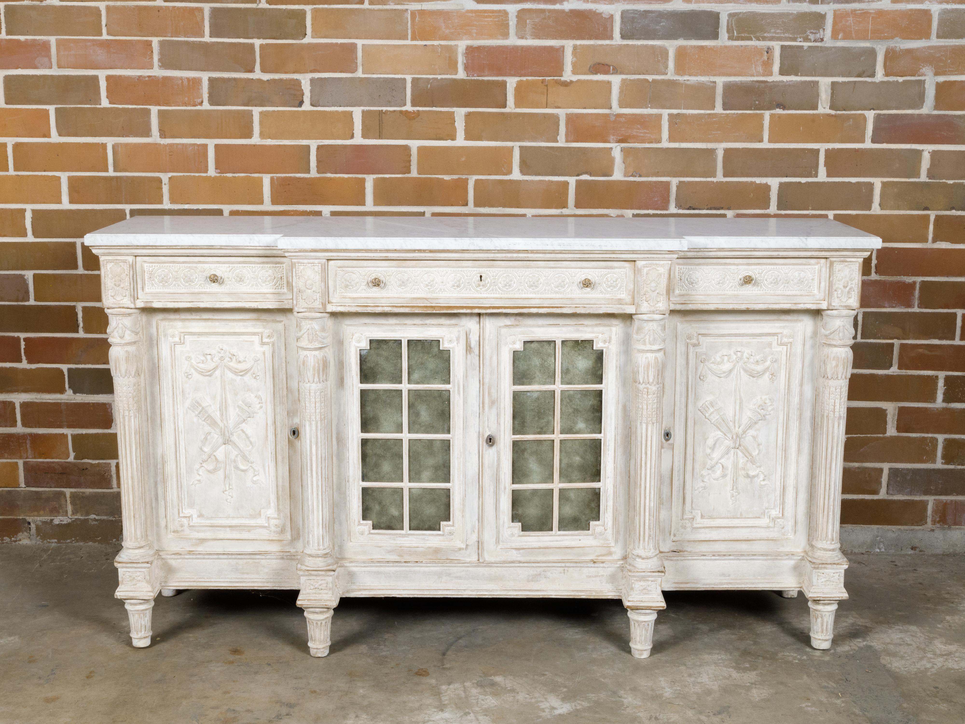A French Neoclassical style painted and carved wooden breakfront buffet from the 19th century with white marble top, three drawers over three doors. This 19th-century French Neoclassical style buffet effortlessly combines artistry with