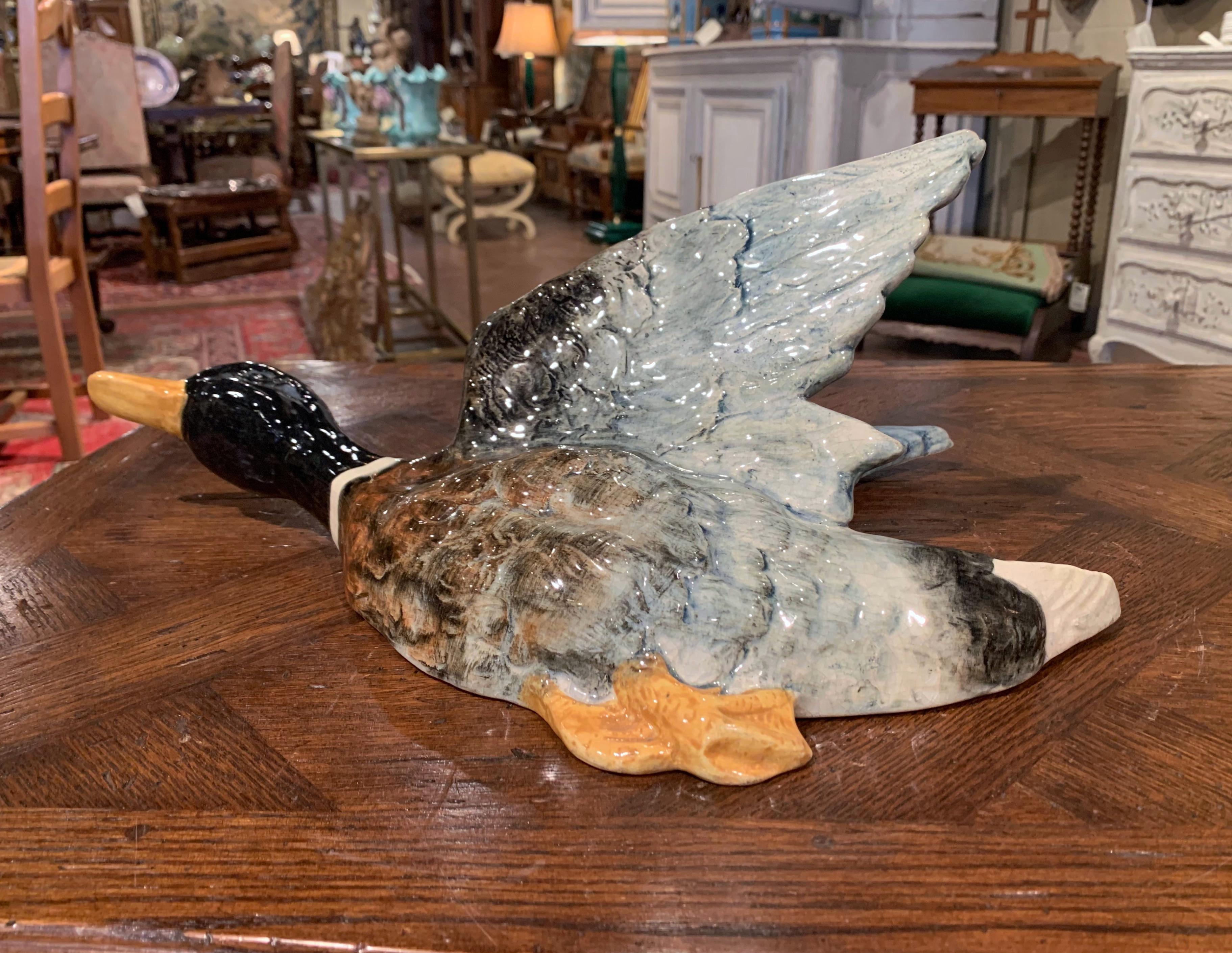 Decorate a kitchen, a game room with this elegant antique Majolica sculpture; crafted in France circa 1890, the ceramic piece features a flying duck with hole between the wings for dry flowers. The large colorful bird sculpture is in excellent