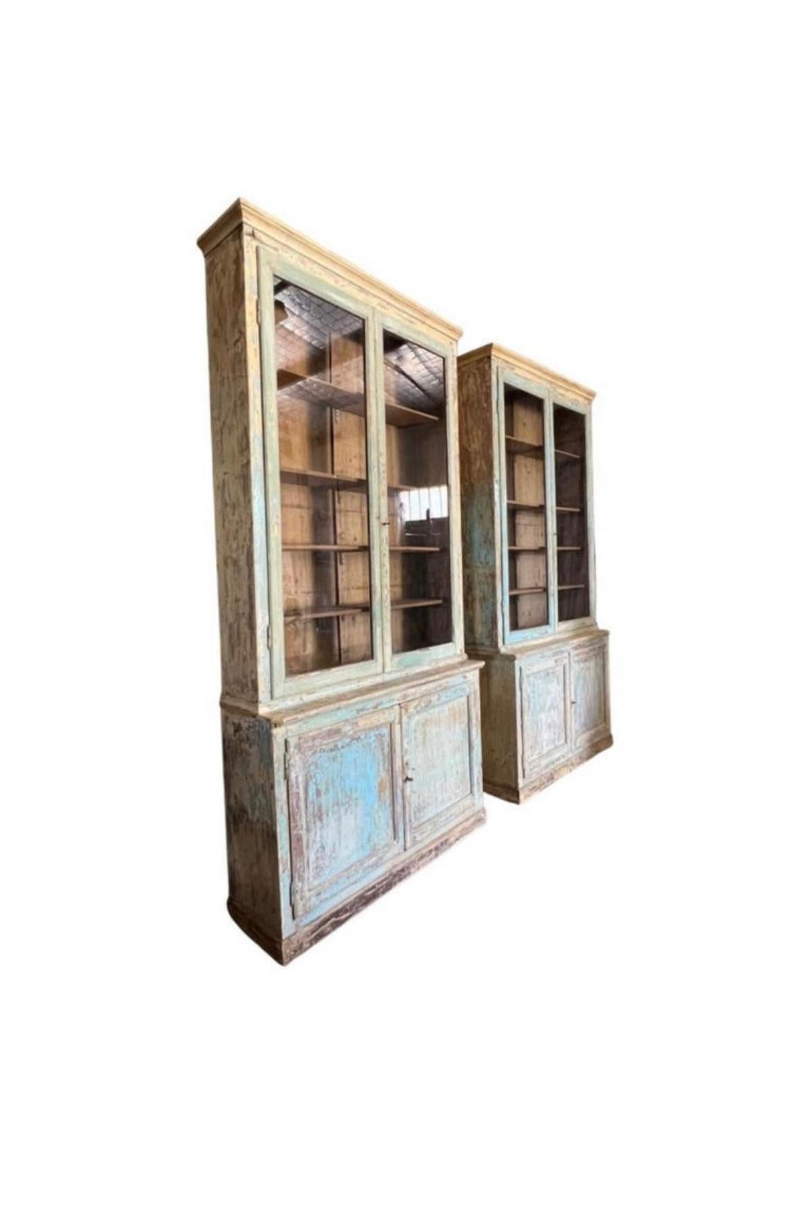 A magnificent pair of 19th Century French Bibliotheques with glass front doors on the upper cabinets. Dry scrapped with natural wood showing in certain areas with cream, green and blue shades. Stunning pieces that make a statement for any room.